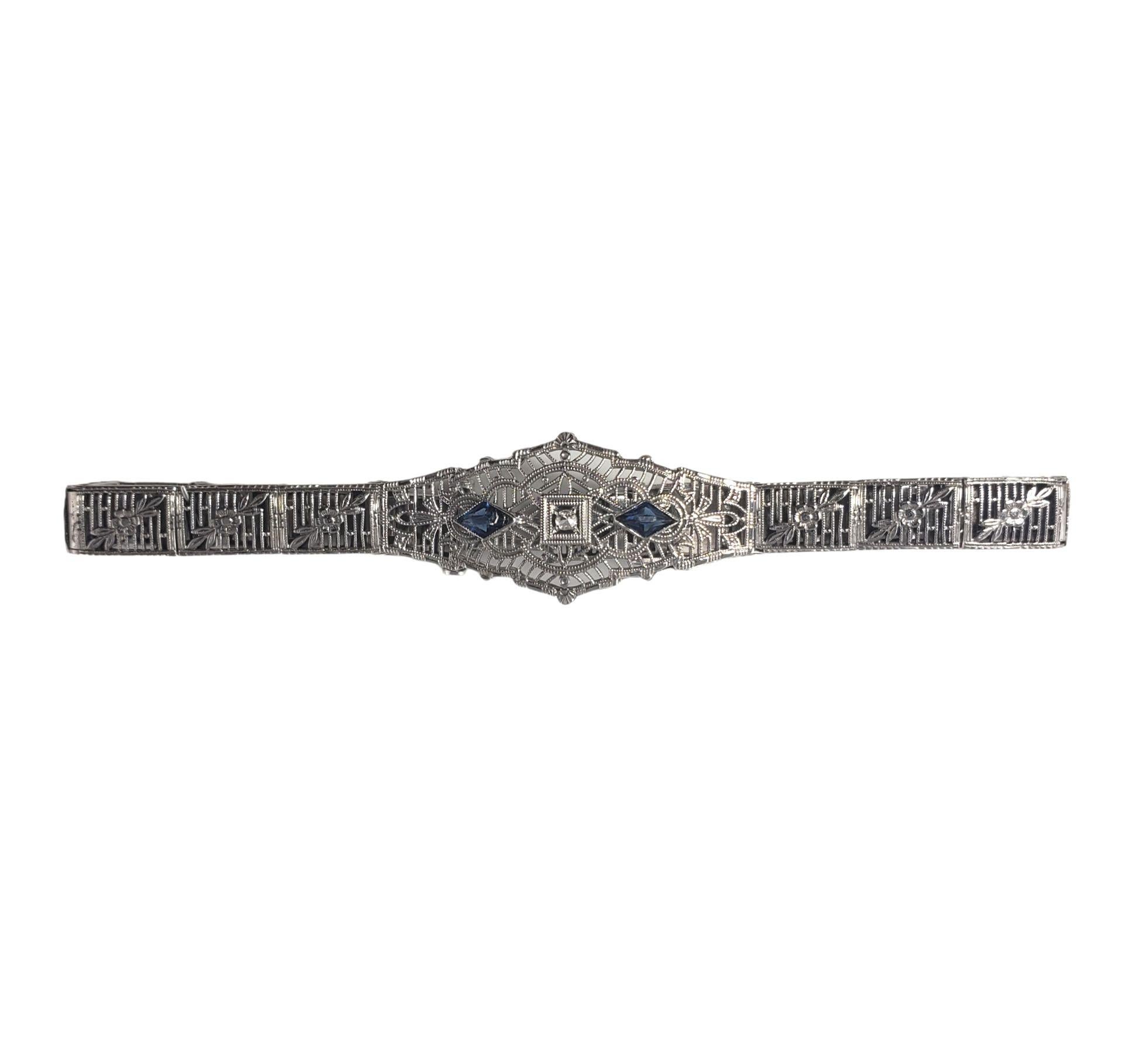 Vintage 10 Karat White Gold Filigree Diamond and Blue Glass Bracelet-

This lovely bracelet features one round single cut diamond and two blue glass pieces set in beautifully detailed 10K white gold filigree. Width: 15 mm.

Approximate diamond