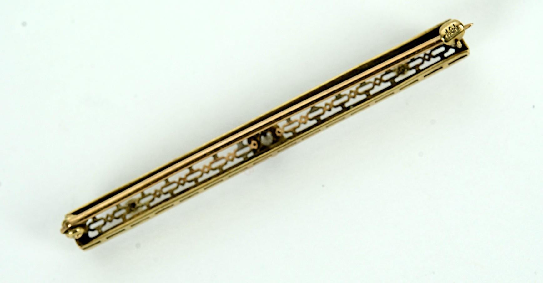 Vintage 10 Karat Yellow Gold, Diamond and Seed Pearl Bar Pin or Brooch. Early 20th c with a central 2.5mm full cut diamond set in a floral mount and a pair of 2mm seed pearls in a beautifully detailed, pierced and decorated frame, hallmarked 10K.