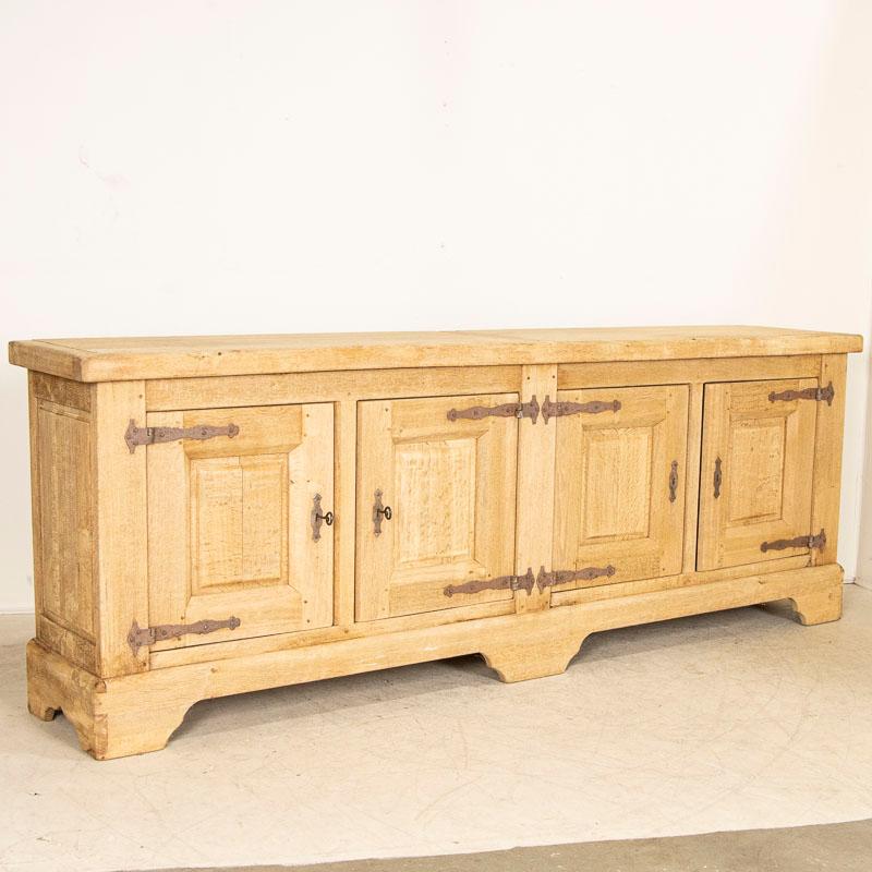This vintage long oak sideboard has been bleached giving it a fresh and welcoming look for today's modern home. The four doors open to reveal interior shelves and simple drawers. At almost 10' long, it will serve well as a buffet, sideboard or