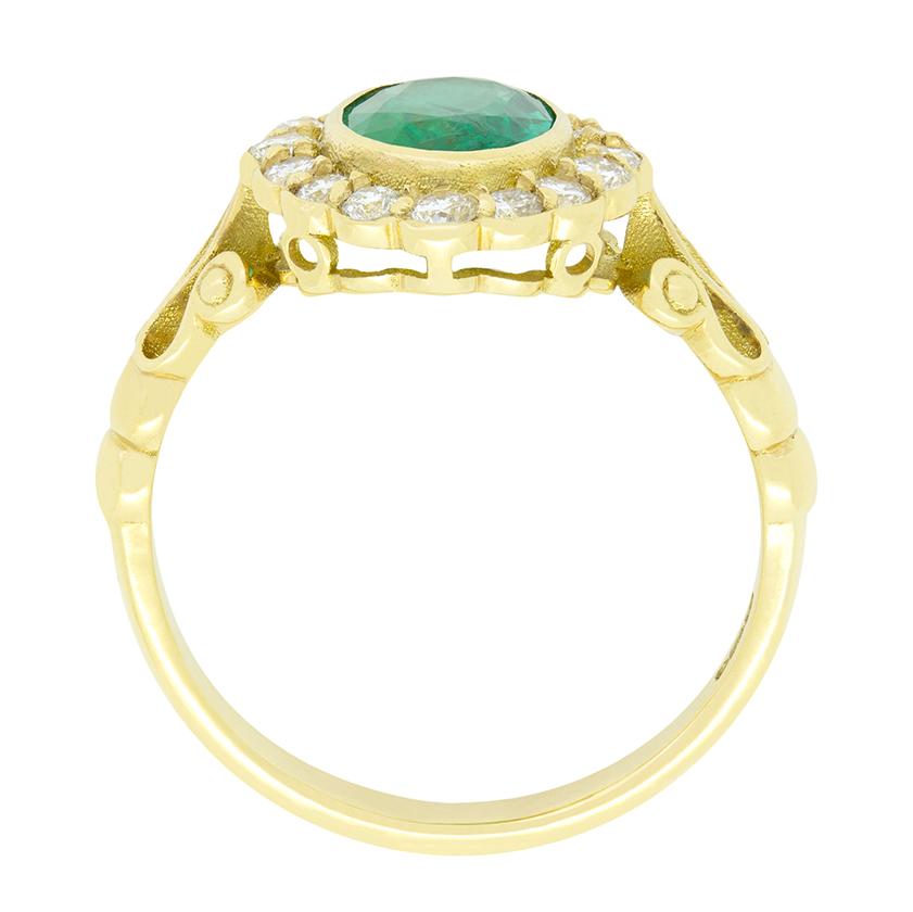 Ein leuchtender Smaragd von 1,00 Karat steht im Mittelpunkt dieses Vintage-Cluster-Rings. Der Smaragd ist ein oval geschliffener Stein und ist sicher in 18 Karat Gelbgold gefasst. Der Smaragd in der Mitte ist von einem Halo aus runden Diamanten im