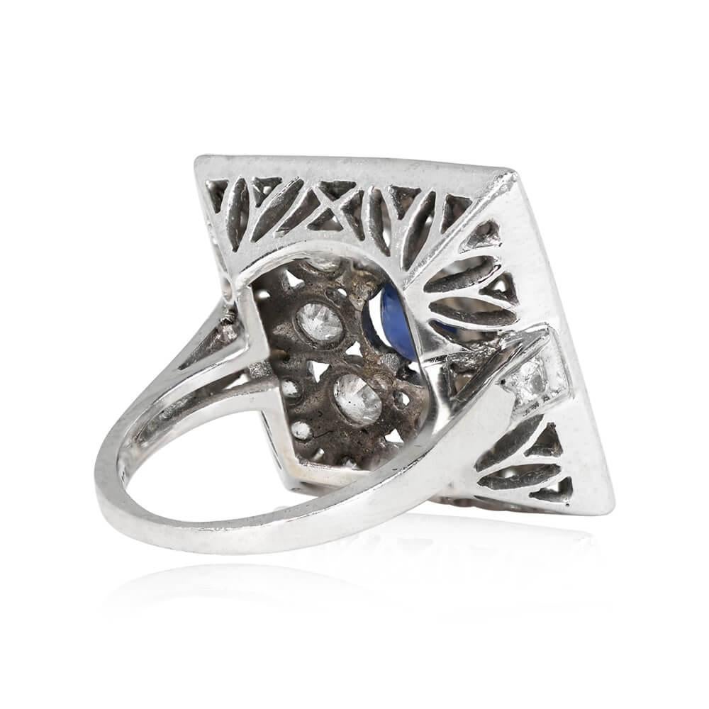 A vintage ring with a round-cut natural sapphire at the center, weighing approximately 1.00 carat and held in prongs. The center stone is surrounded by a floral halo of old European cut diamonds set within half-bezels. An outer border of old