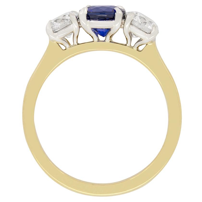 Questo intramontabile anello trilogy degli anni '70 presenta un vibrante zaffiro blu al centro, affiancato da una coppia di diamanti tondi brillanti. Lo zaffiro centrale è una pietra di taglio rotondo del peso di 1,00 carati. Gli zaffiri laterali