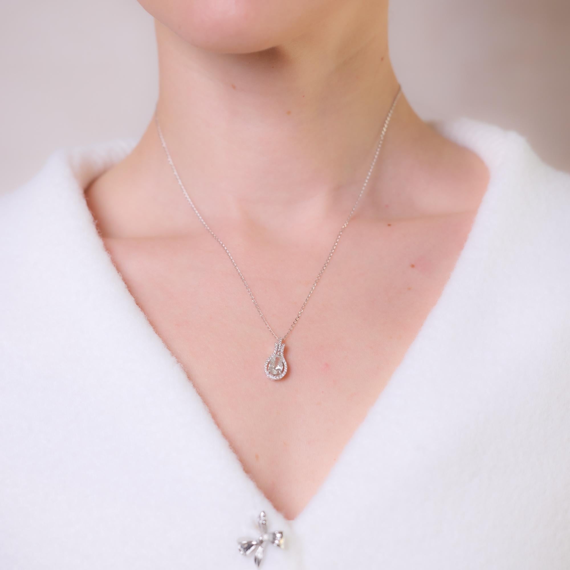 Diese Vintage-Halskette aus 18 Karat Weißgold präsentiert einen AIG-zertifizierten birnenförmigen Diamanten von 1,01 Karat, Farbe H, Reinheit SI3, der elegant von 41 runden Diamanten im Brillantschliff von insgesamt etwa 0,20 Karat, Farbe G-H,