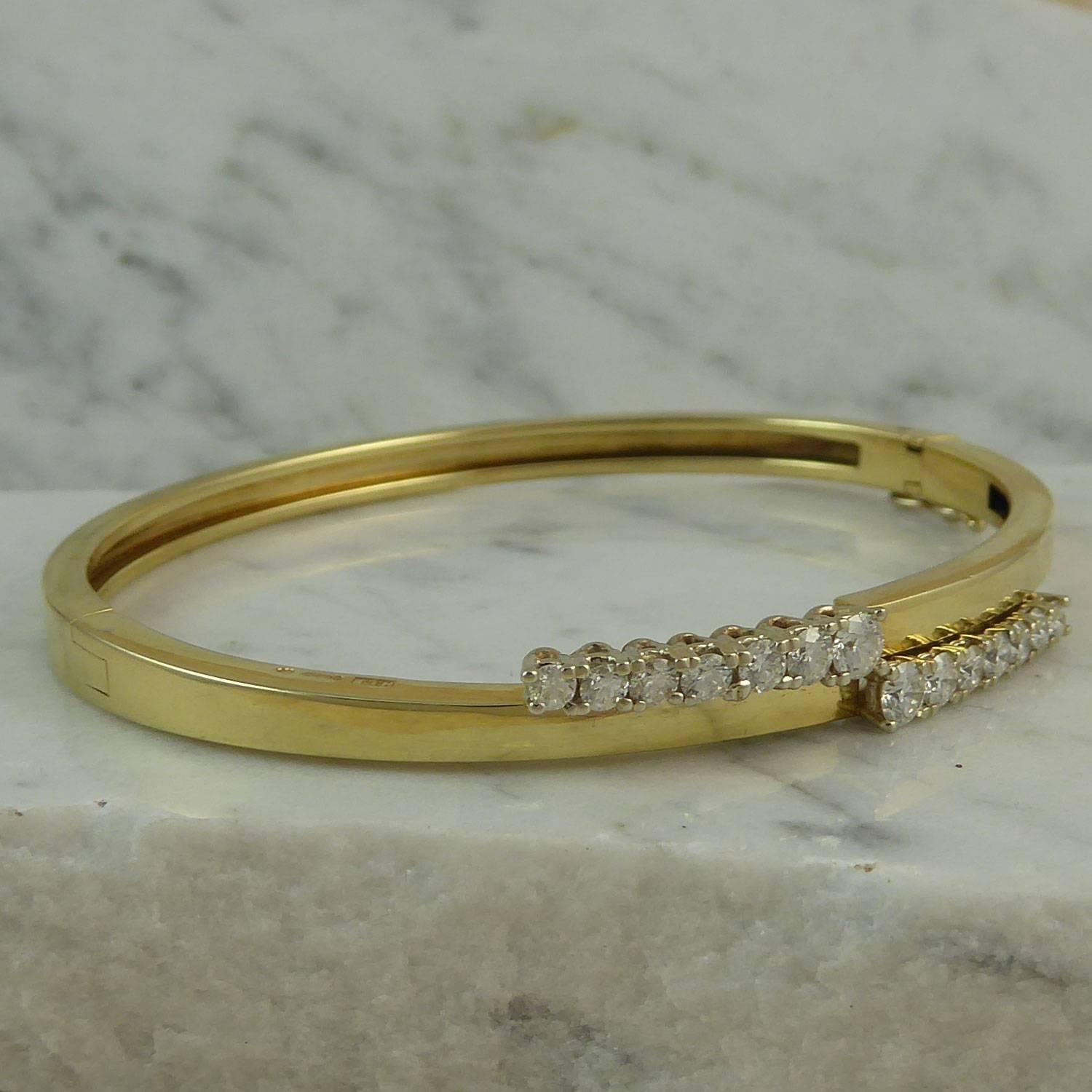 A recent vintage diamond bangle set with a total of 1.02ct brilliant cut diamonds set in two overlapping rows to the front half of the bangle.  Each row of diamond comprises seven stones, each approx. 3.2mm to 2.2mm diameter, claw set to a polished