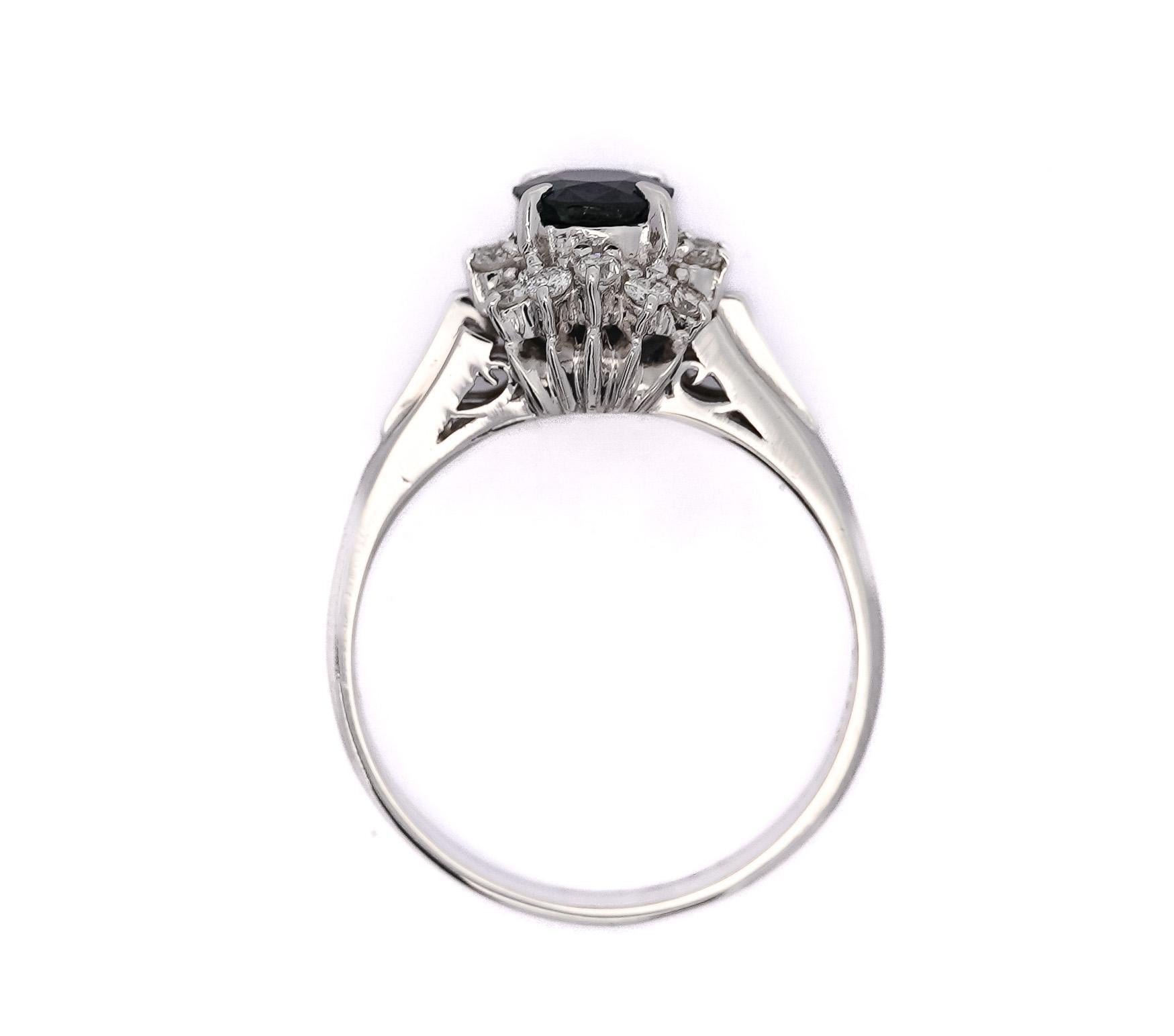 1.04 Carat Sapphire and Round Cut Diamond in Filigree Platinum Ring. The ring hold a beautiful, eye-captivating, prong-set, navy blue sapphire stone in the center surrounded by a round cut diamond halo. The platinum band has filigree detailing and