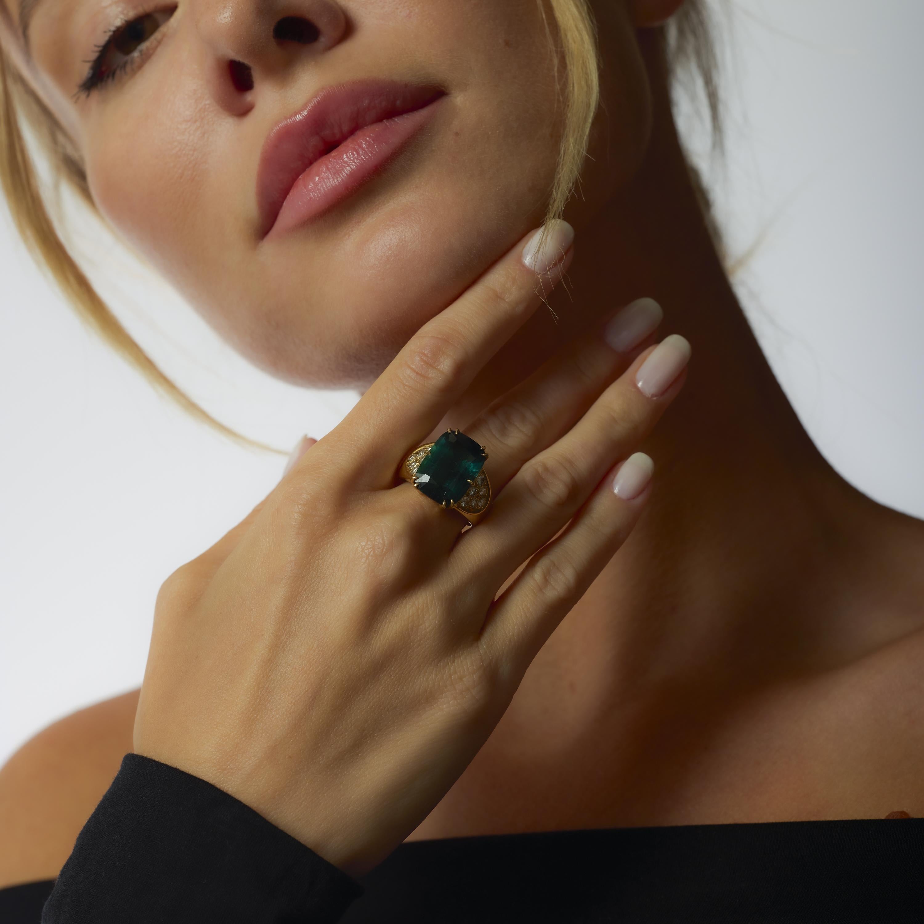 This vintage ring showcases a lush 10.40 carat greenish blue tourmaline framed by brilliant white diamonds in rich 18k yellow gold.