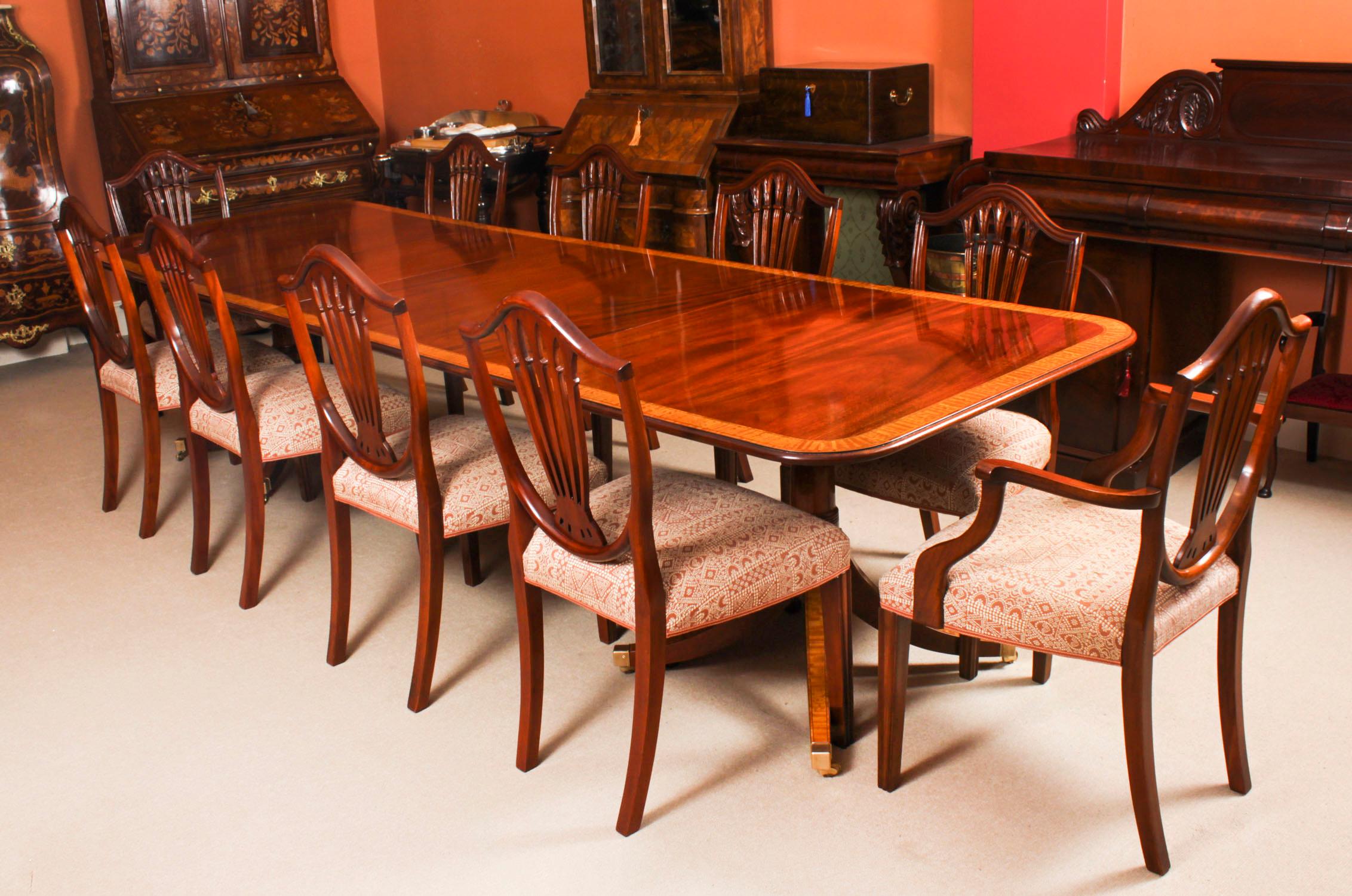 Il s'agit d'une table de salle à manger Vintage Regency Revival de superbe qualité, datant de la seconde moitié du 20ème siècle.

Le plateau de la table a été réalisé en acajou flammé et présente un superbe décor de bandes transversales en bois