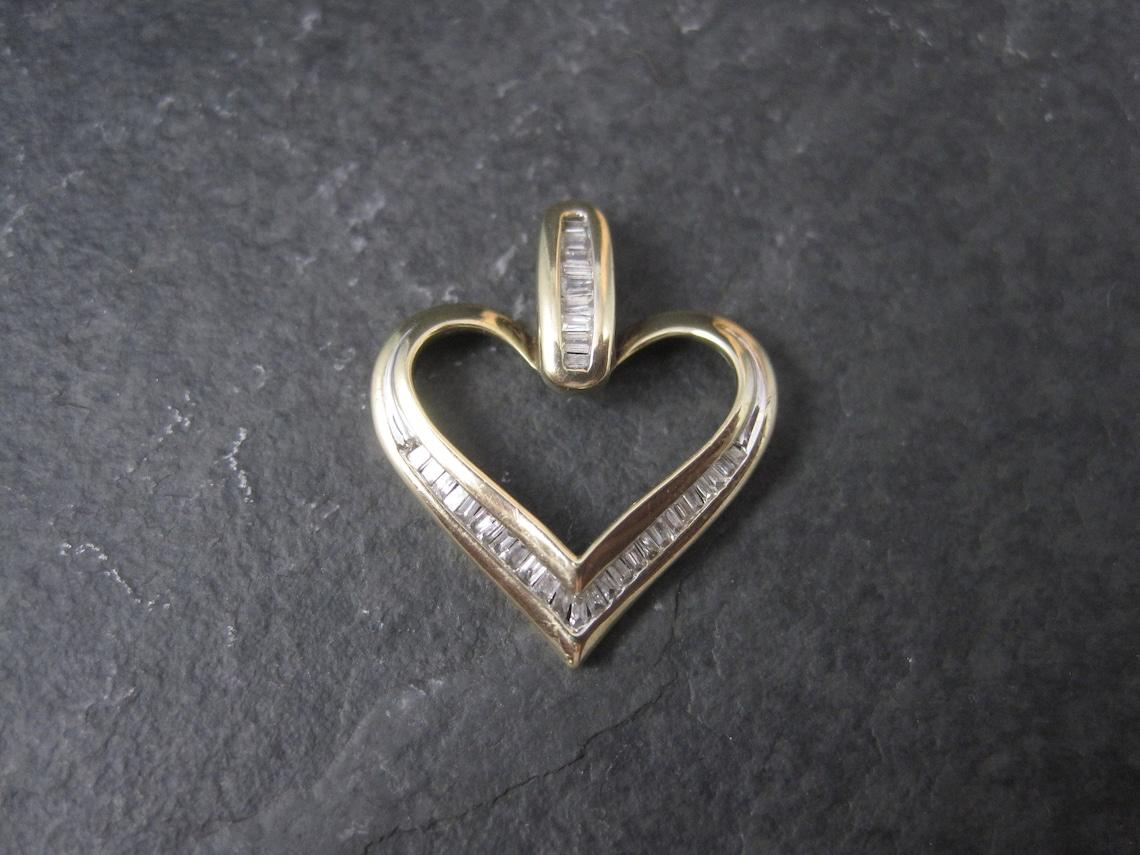 This beautiful vintage heart pendant is 10K yellow gold with an estimated .25 carats in natural baguette cut diamonds.

Measurements: 3/4 by 15/16 of an inch

Condition: Excellent