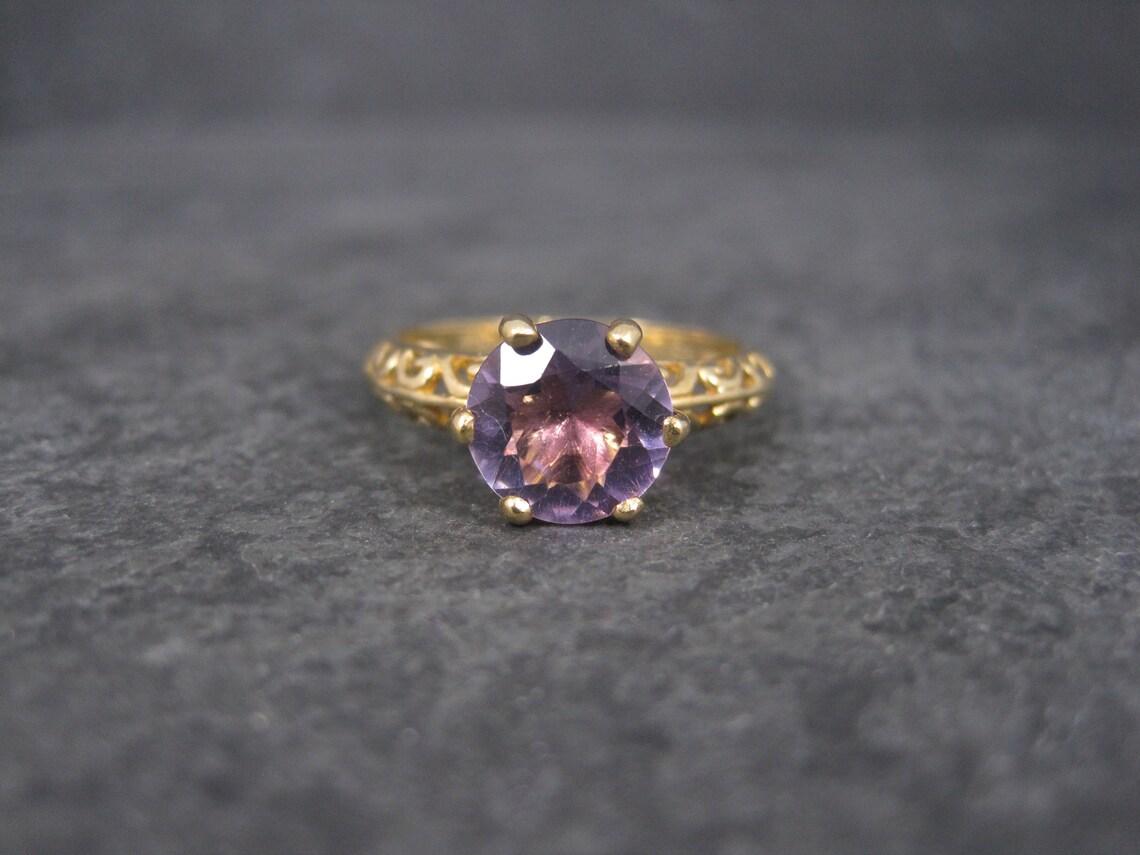 This gorgeous estate solitaire is solid 10k yellow gold.
It features a 2 carat, round cut natural amethyst set in a filigree design.

The face of this ring measures 9mm with a rise of 7mm off the finger.
This ring is a size 7.

It is in fabulous