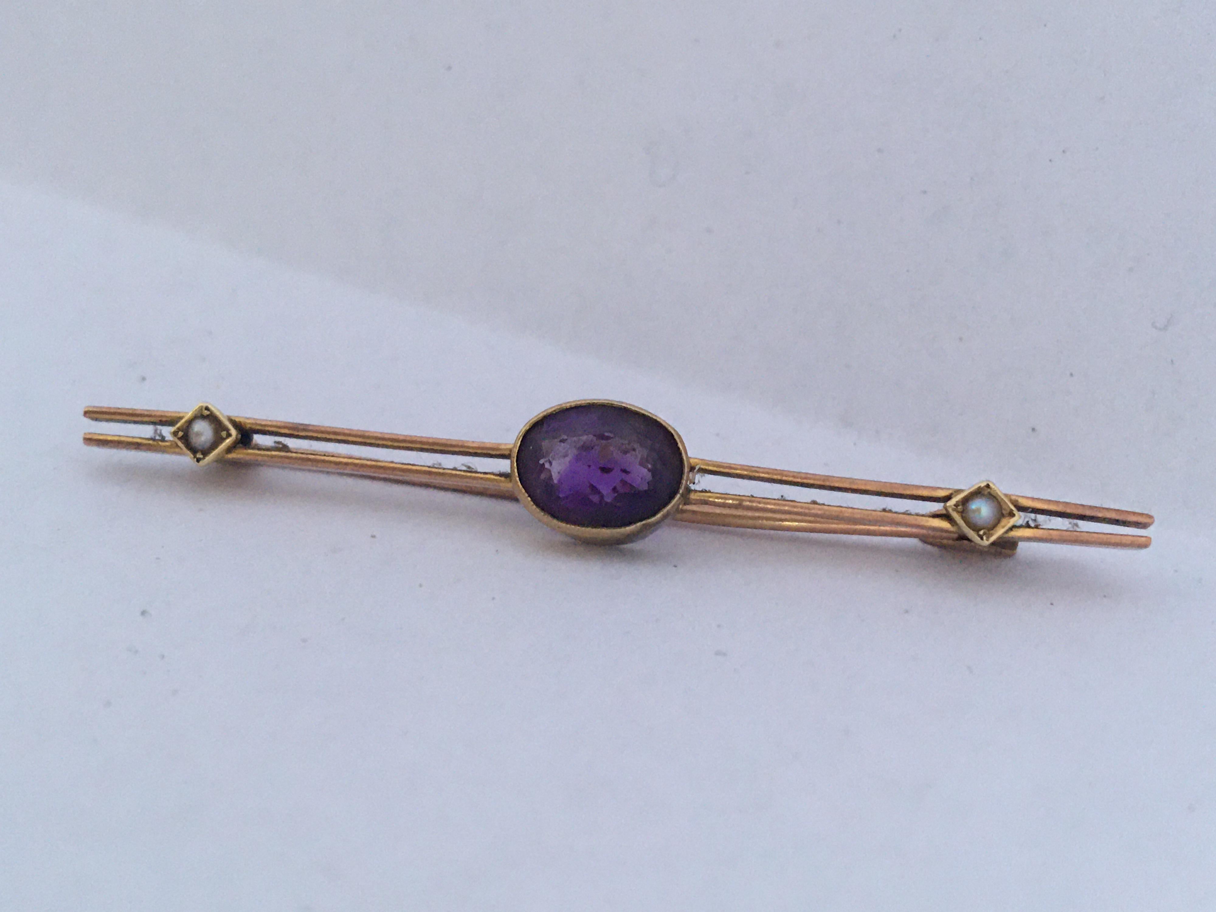 This elegant pin made of 10 Karat yellow gold and is hallmarked. It has a sparkling faceted deep purple amethyst gemstone which is a define set and open backed. a set of pearl on each side. This is in good vintage condition. It has a good pin,