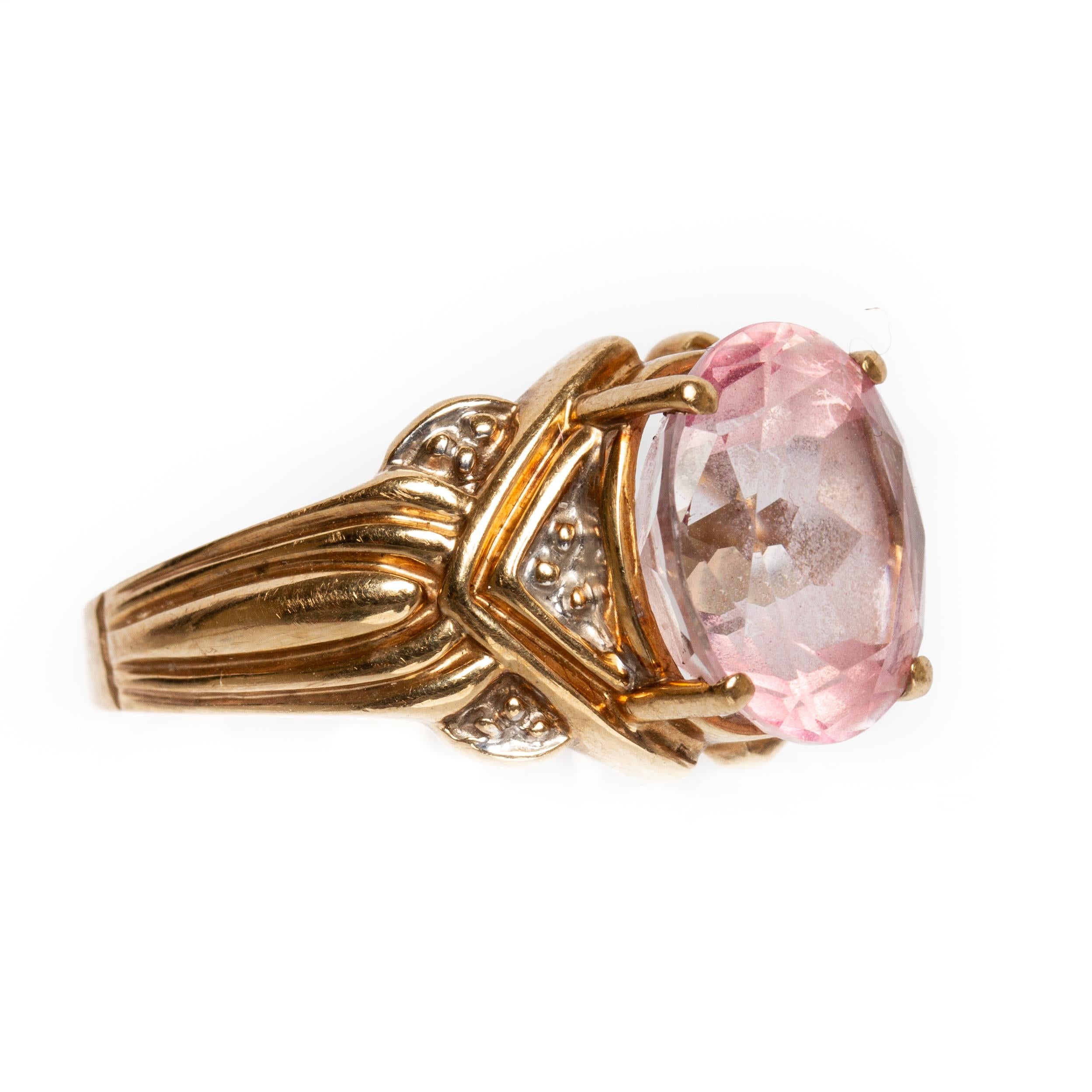 A 10K gold ring with faceted pink sapphire. The ring has an Art Nouveau style with two-tone fluted shoulders and shank. 10K yellow and white gold. Ring Size 8.25. Hallmarks: R 10K. Total Weigh 3.20dwt. 1 Stone, Oval faceted and measures 12.00mm x