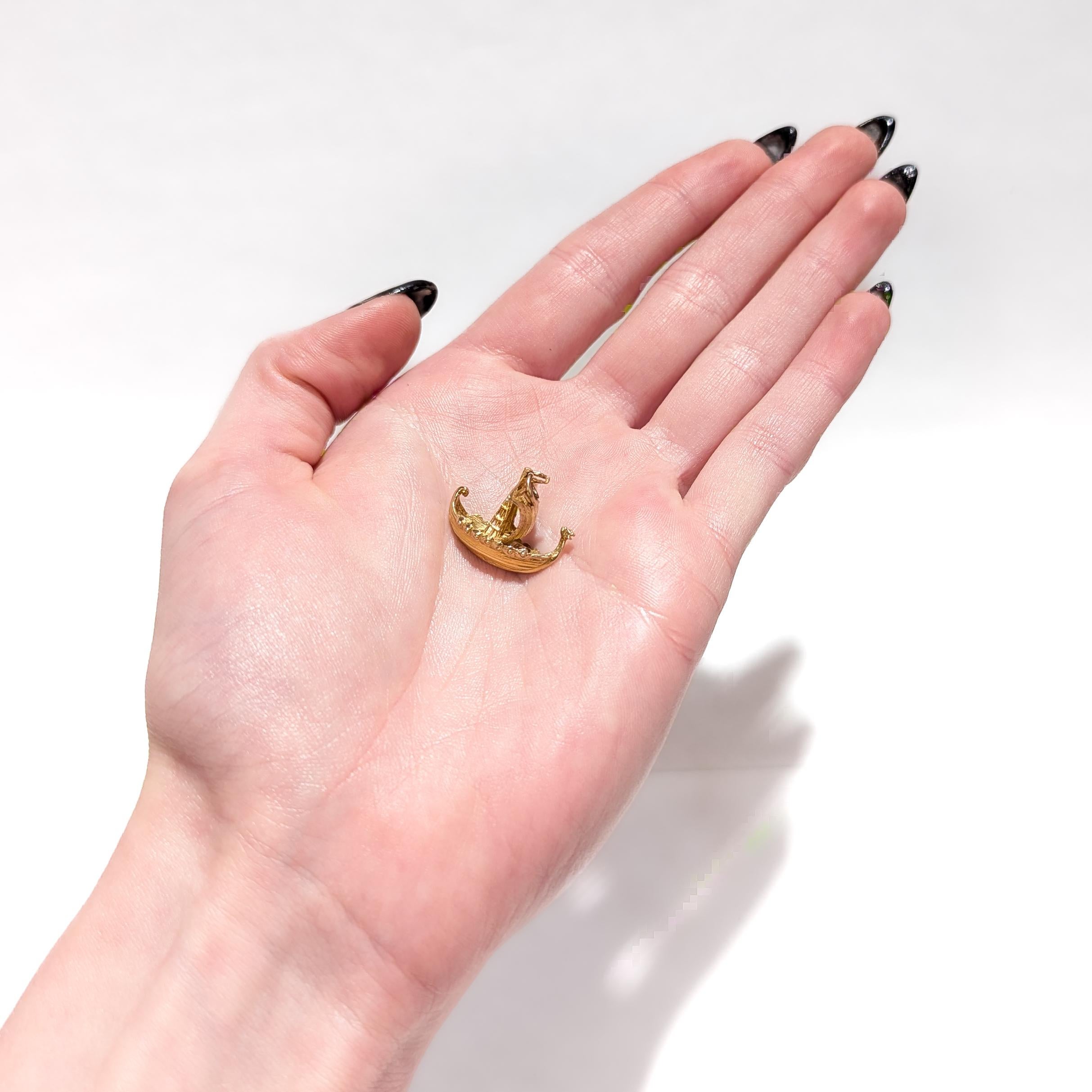 A fine vintage gold charm for a bracelet.

In 10 karat yellow gold. 

In the form of a longship that is commonly associated with Norsemen/Vikings. 

With a single sail, 12 rowing benches, and a figural dragon's head to the bow.

With a jump ring to
