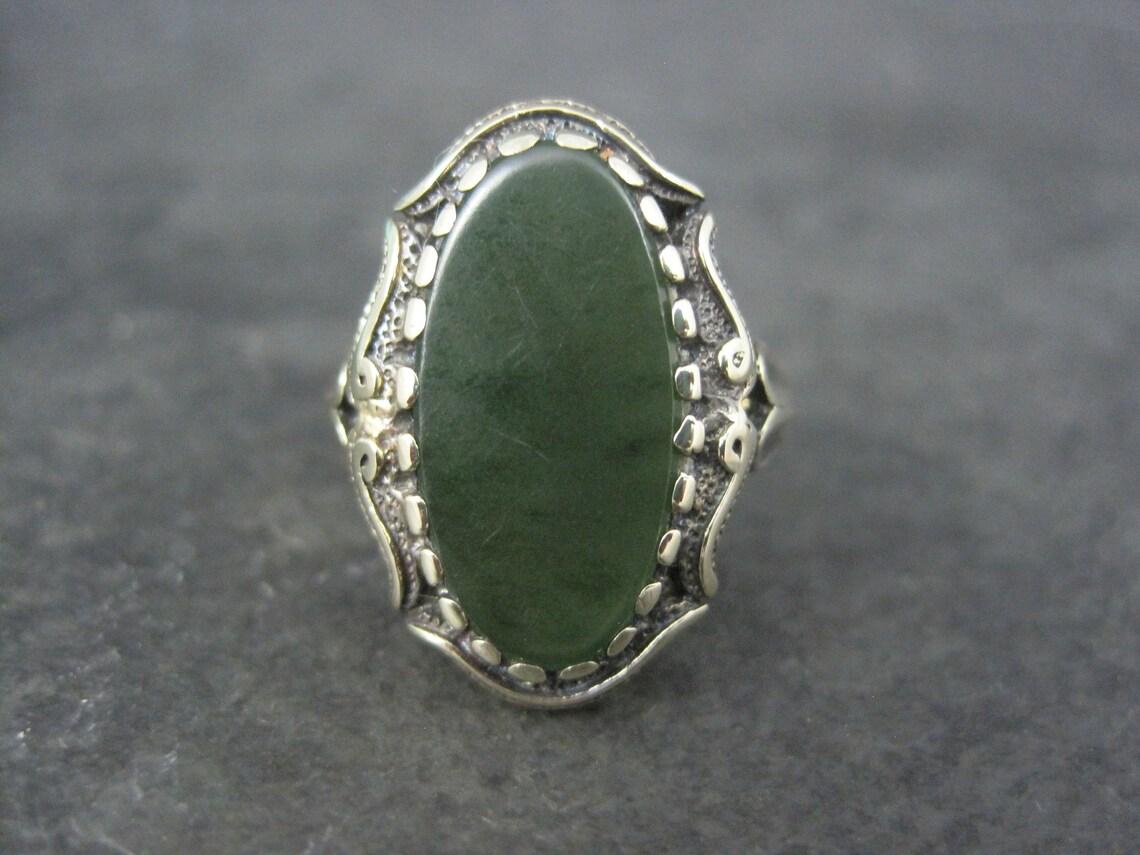This gorgeous estate ring is 10K gold with a nephrite jade gemstone.

The face of this ring measures 13/16 of an inch north to south.
Size: 6 1/2
Marks: 10K

Condition: Under magnification, you can see the stone has minor surface abrasions -
