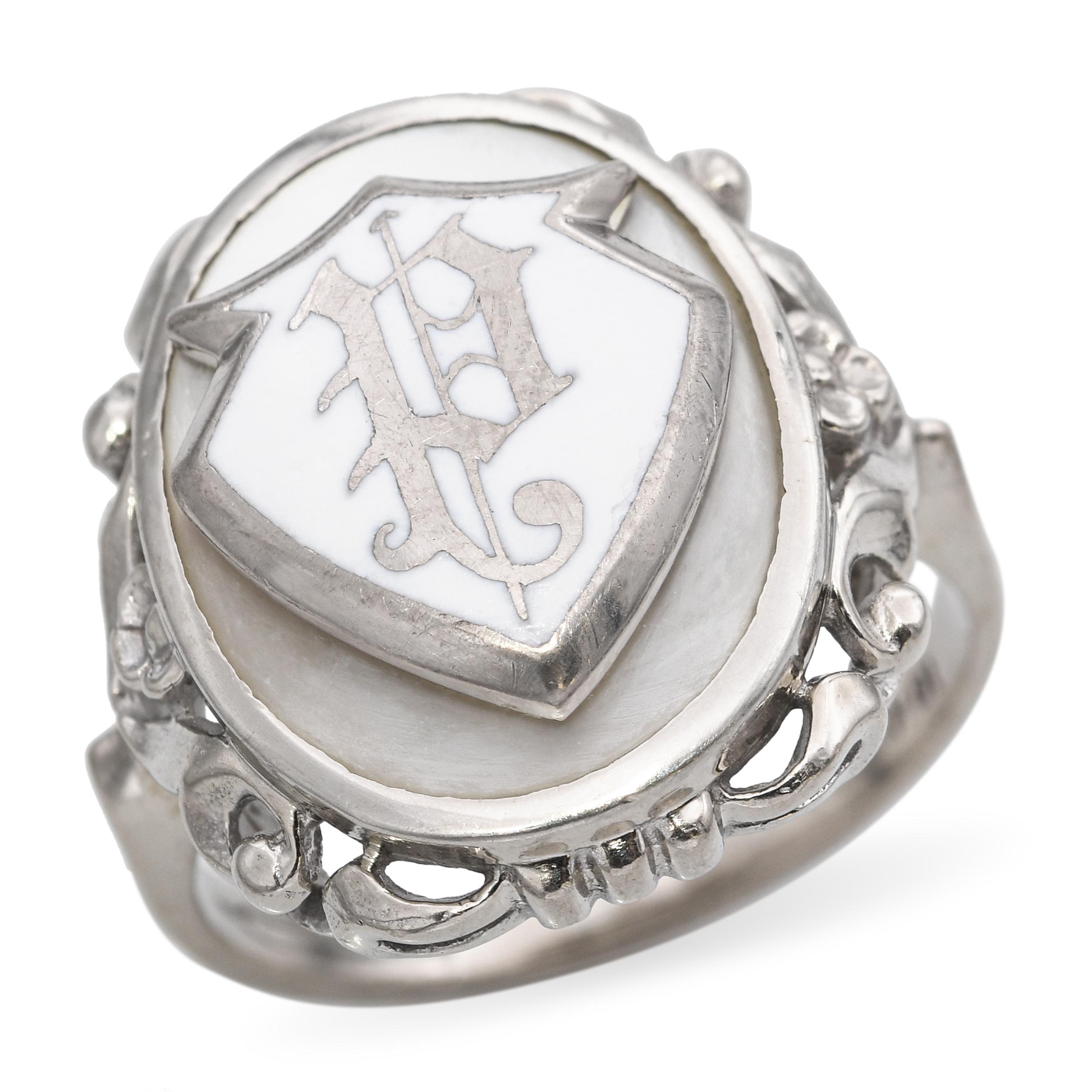 Questo anello vintage è realizzato in oro bianco 10k e presenta un luminoso intarsio di madreperla, elegantemente incorniciato da un monogramma personalizzato in smalto nero. La morbida iridescenza della perla contrasta meravigliosamente con la