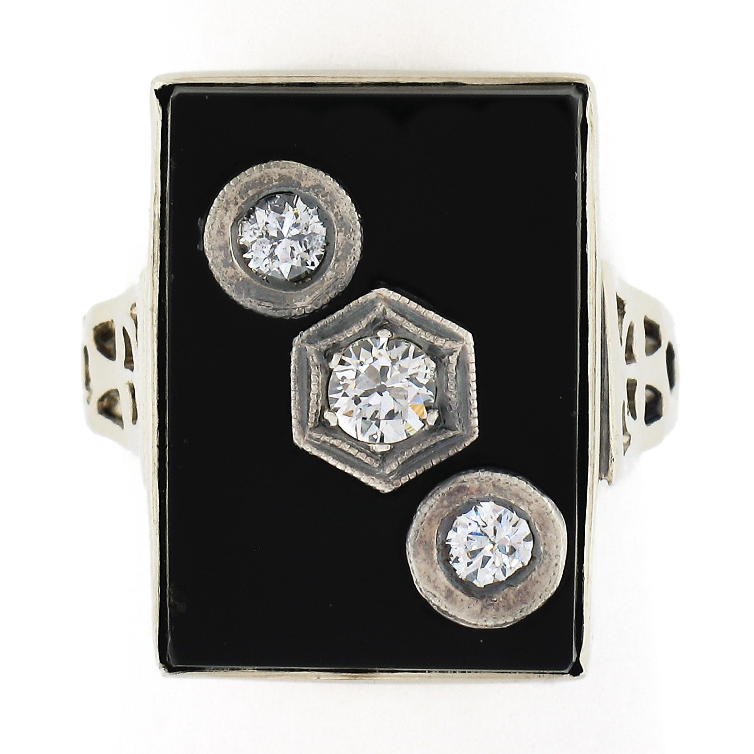 This outstanding vintage ring was crafted in solid 10k white gold and features a large, polished, rectangular cut black onyx stone adorned with 3 old cut diamonds neatly and individually set at a diagonal across its top. The fine onyx gemstone has a