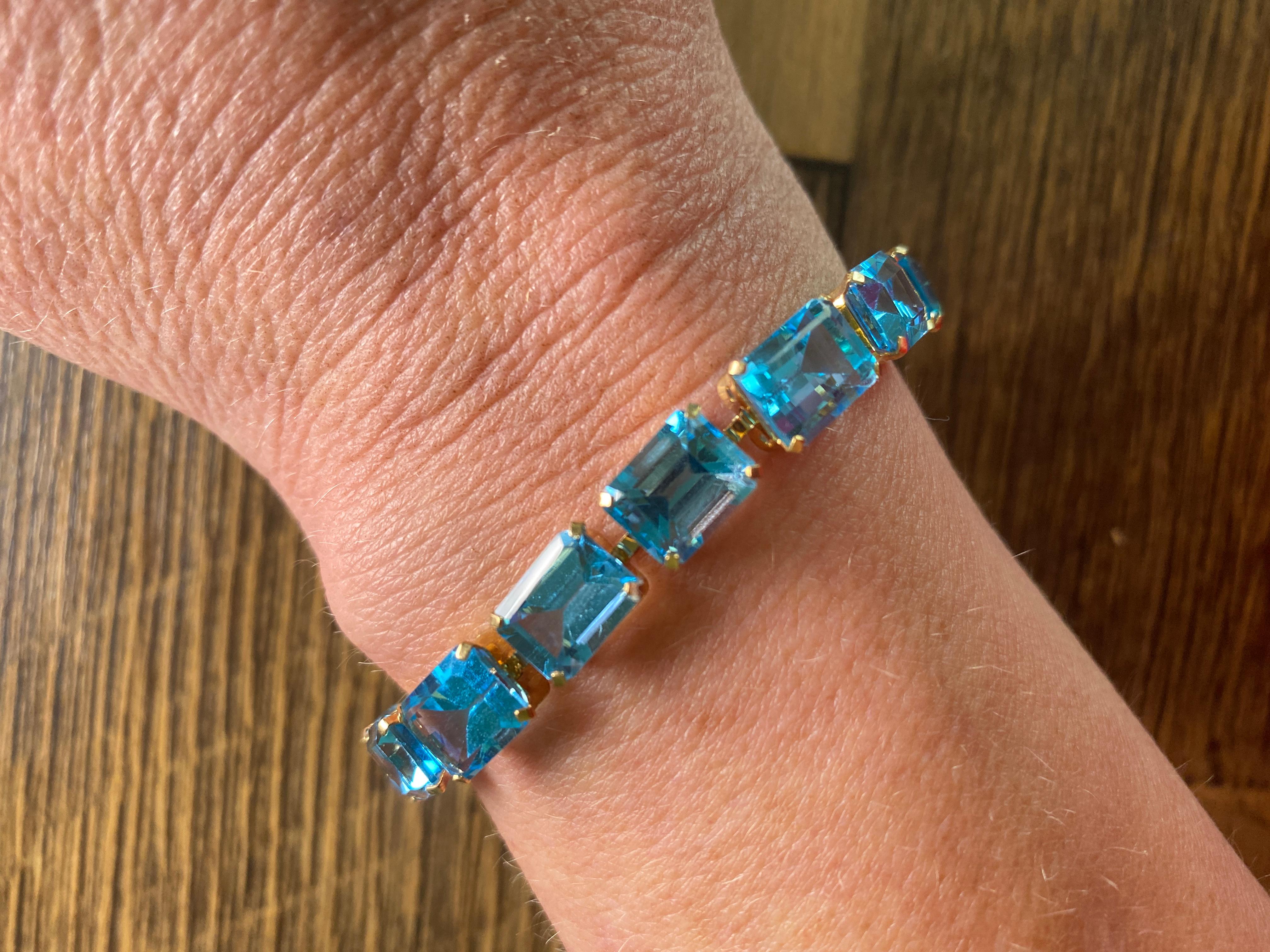 Vintage, 10K Yellow Gold Baguette Blue Topaz Tennis Bracelet, 7 1/2 inches.  Delicate 10kt gold bezels hold each stone with prongs. Lovely for day or night. Each stone measures 7mm x 9mm. Approximately 13.5 carats of Blue Topaz stones.