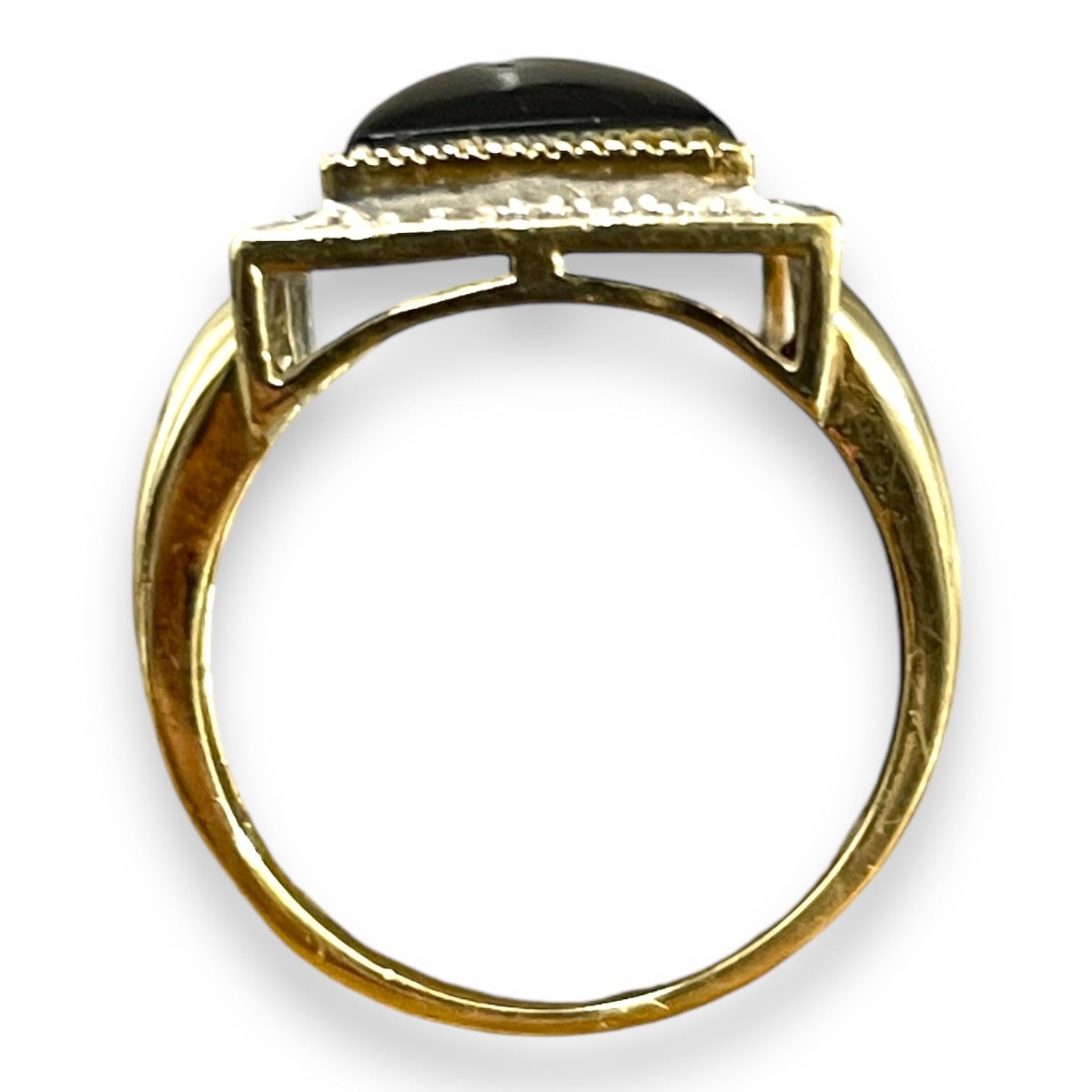 This striking ring features a bold rectangular black onyx, framed by a border of shimmering diamonds. The deep black of the onyx contrasts elegantly with the surrounding sparkle, creating a captivating centerpiece. Set in 10K Yellow gold band, this
