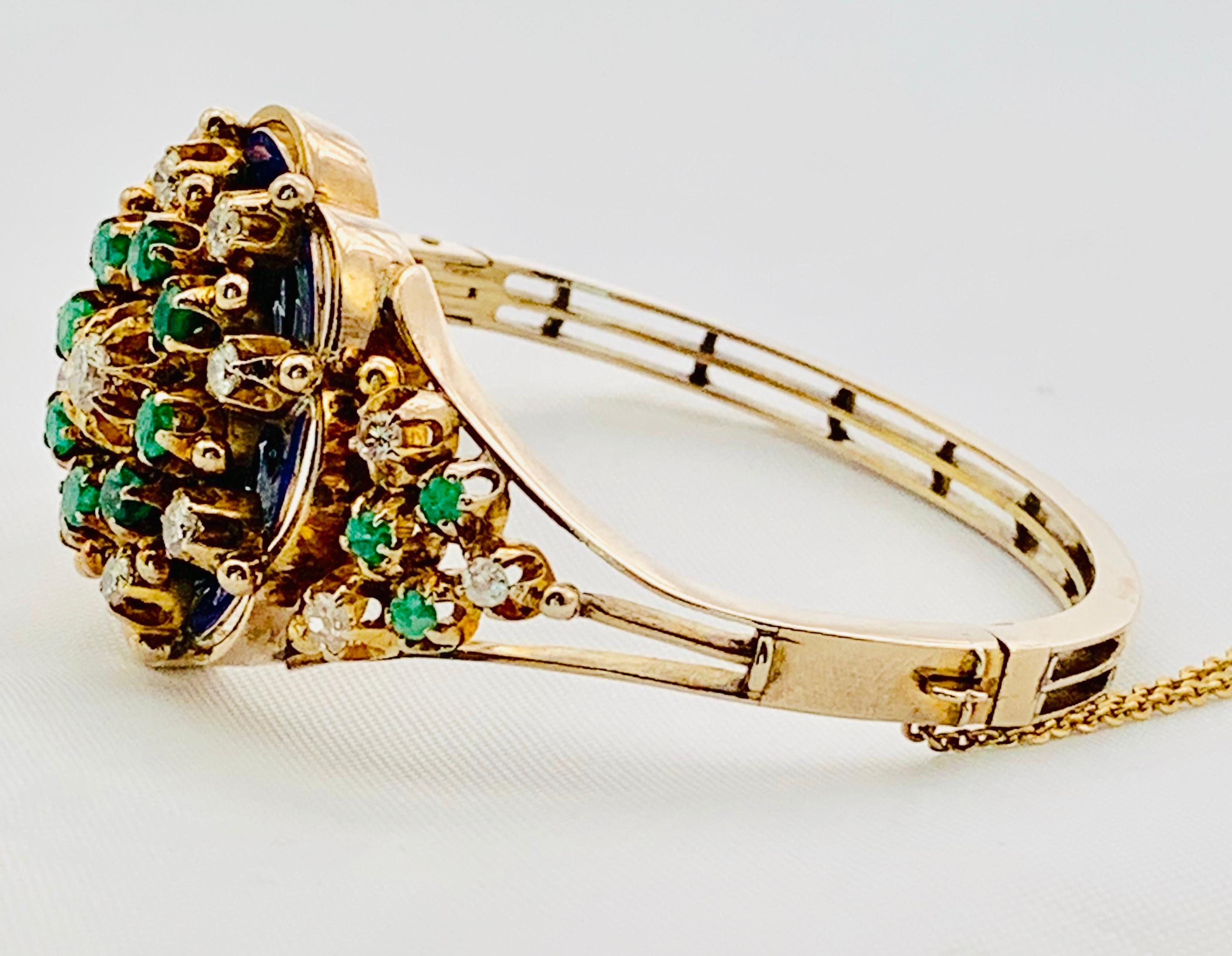 Gorgeous Vintage Bangle Bracelet! This piece is made in 10K Yellow Gold and has a Show Stopping 1.5 inch in diameter Center. Dating from the 1960's or 1970's, this colorful piece features 15 round diamonds and 14 Emeralds that are artfully Accented