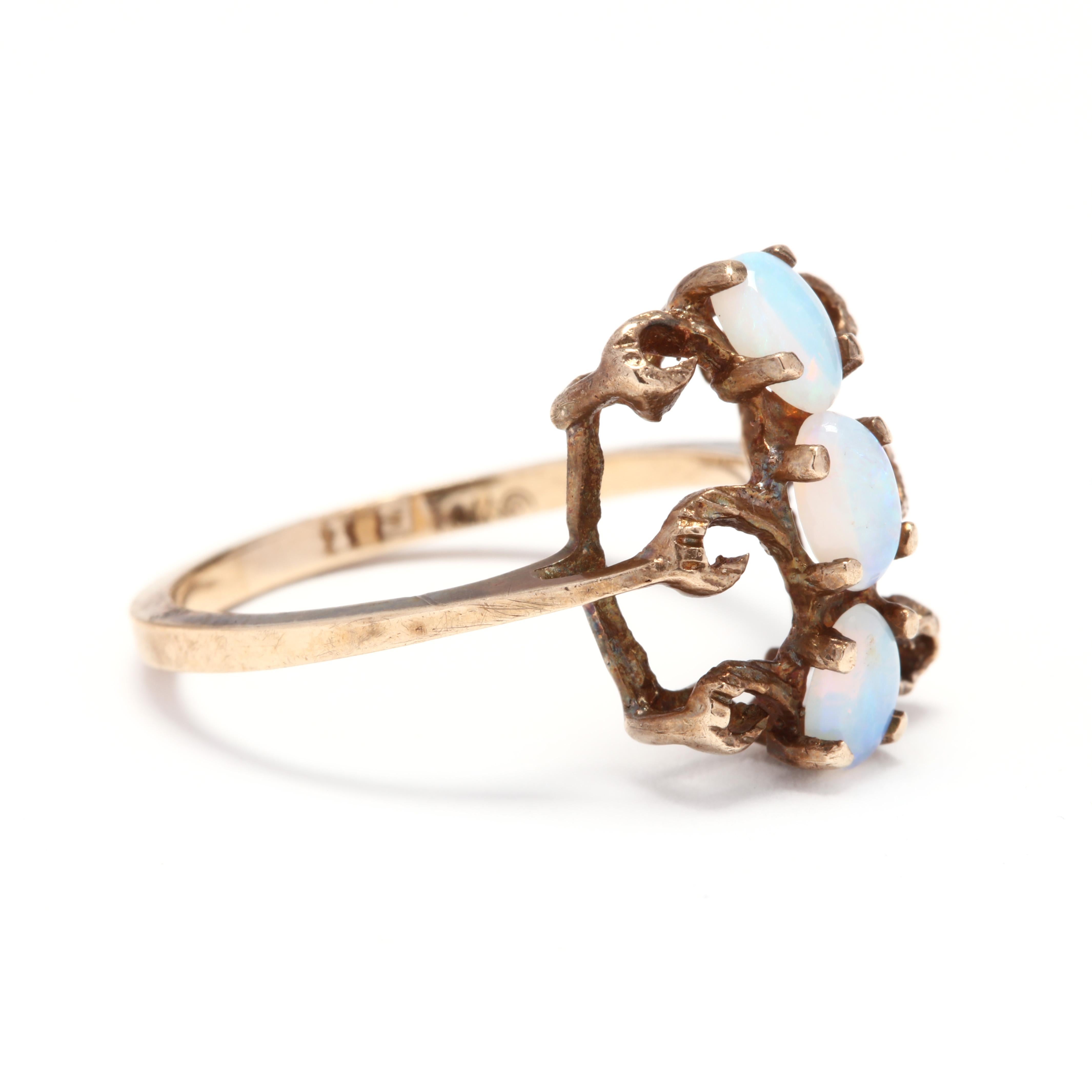 A vintage 10 karat yellow gold and opal statement ring. This ring features a rectangular design with three oval cabochon opals set in a vertical line with swirl motif detailing and a thin shank.

Stones:
- opal, 3 stone
- oval cabochon
- 5 x 3.25