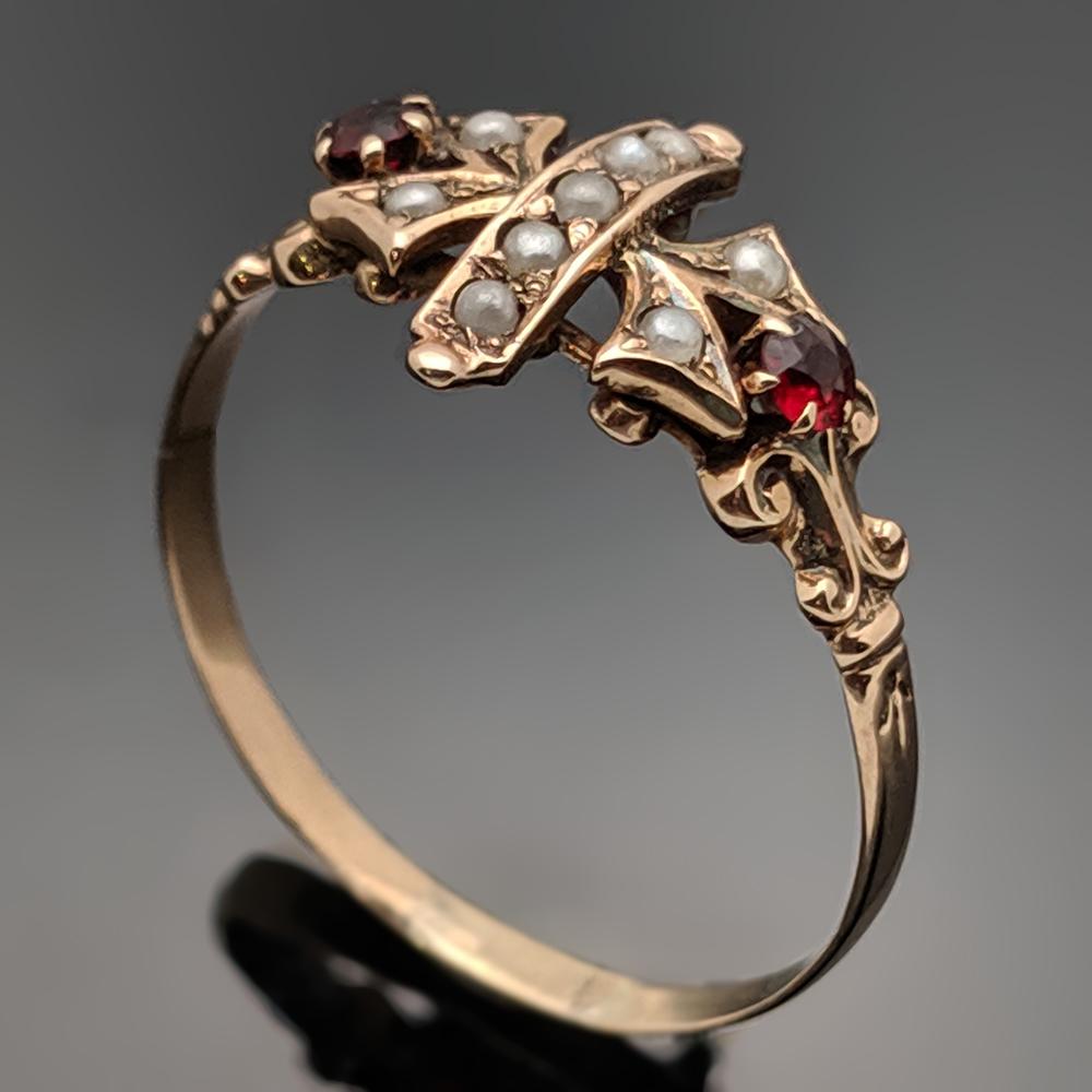 A delicate, vintage 10k rose gold ring featuring two rubies that have an estimated weight 0.07ct. and nine pearls. Estimated weight of gold 1 gr. Etruscan inspired. 

We will size it for you.

