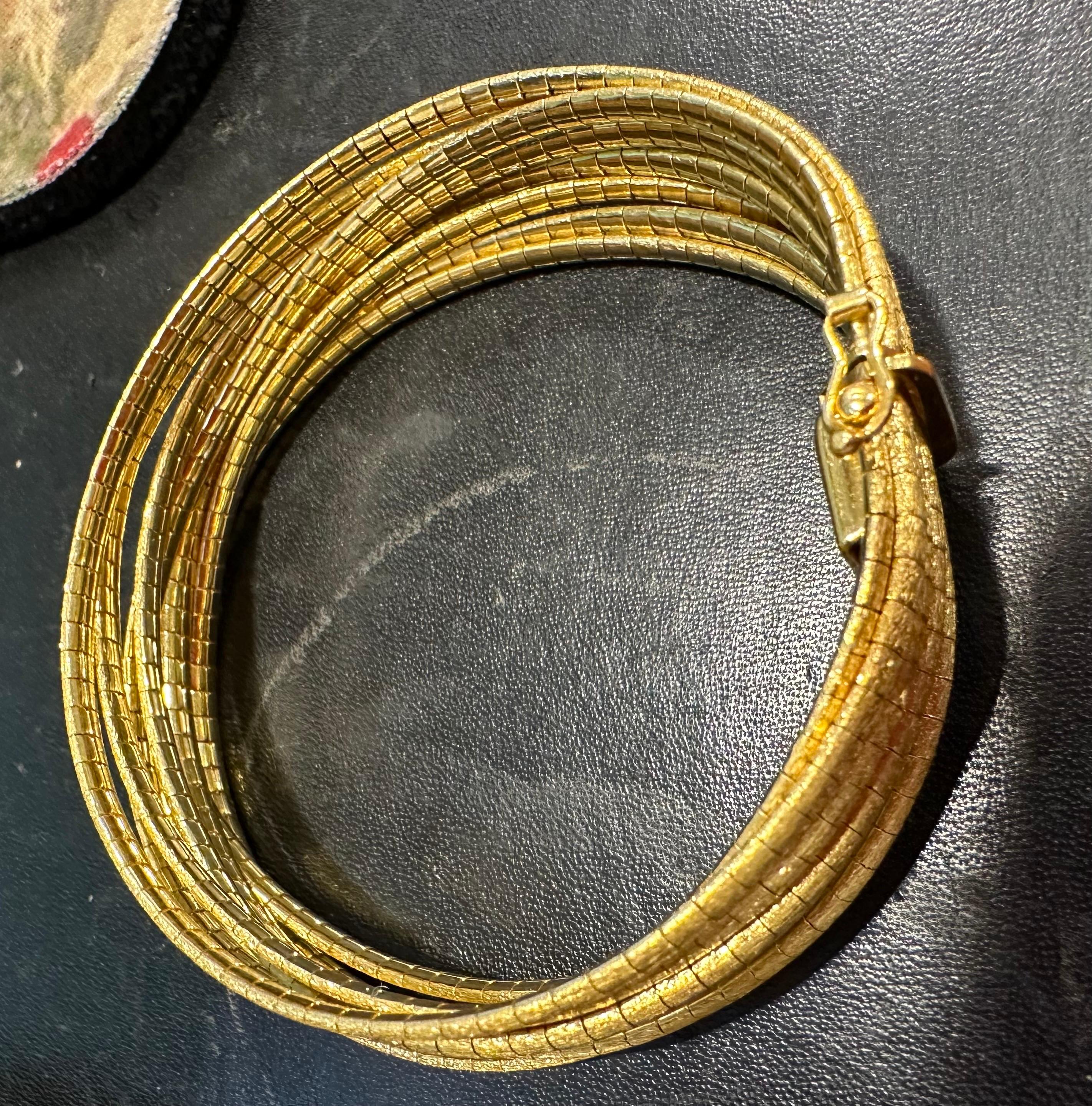 Questo squisito braccialetto vintage in oro martellato presenta un design straordinario con 11 braccialetti collegati, tutti realizzati in oro giallo 18 carati. Con un peso notevole di 69 grammi, questo braccialetto mette in mostra la qualità