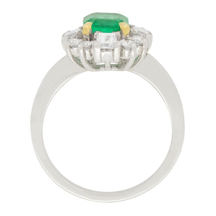 A splendid Emerald weighing 1.10 carat is the focal point of this vintage cluster ring. Set above and to either side is a collection of four carre cut diamonds weighing 0.20 carats each. Set in between each carre cut, is a pair of round brilliant