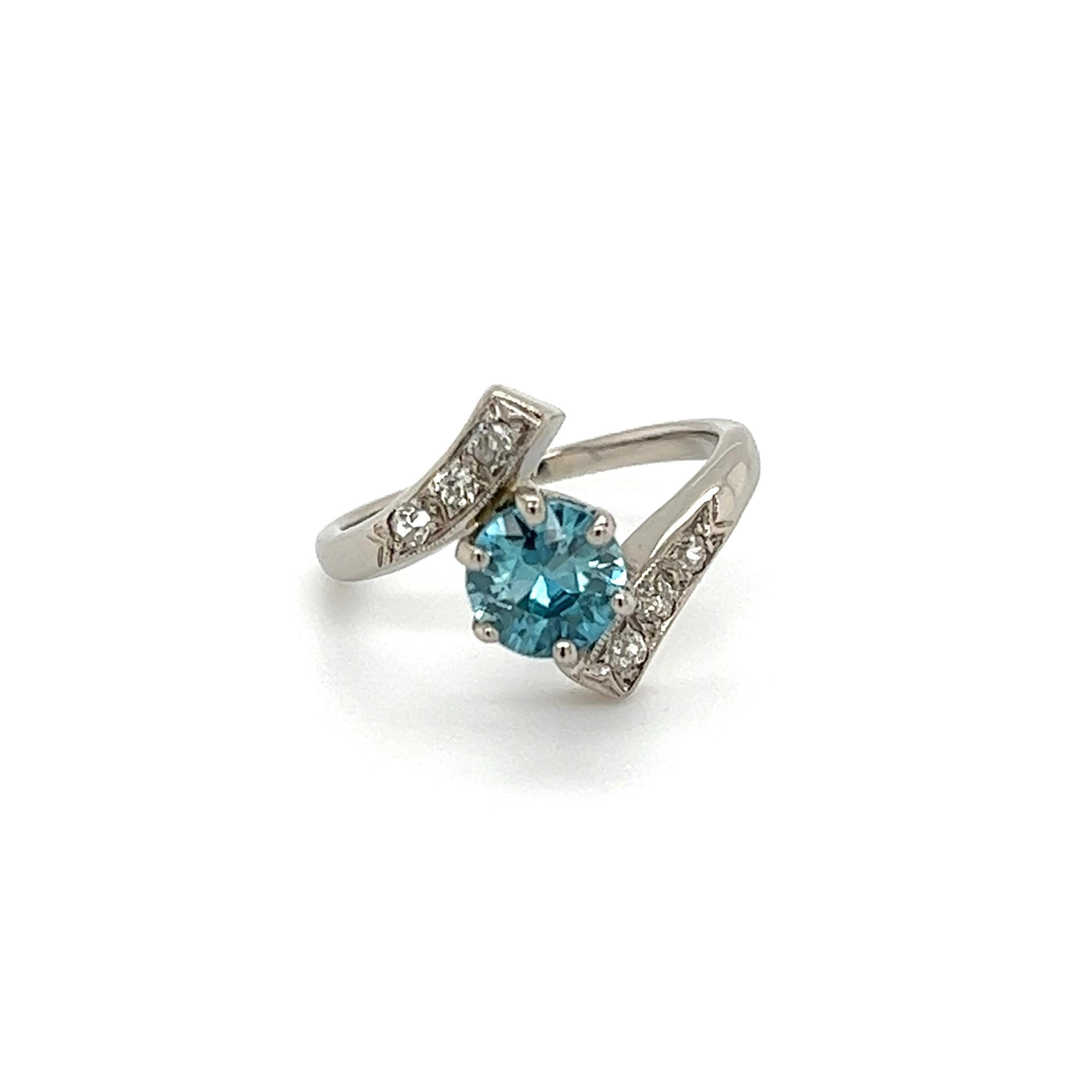 Simply Beautiful! Finely detailed Blue Zircon and Diamond Art Deco Gold Bypass Ring. Centering a Hand set securely nestled 1.13 Carat Round Blue Zircon. Artfully surrounded by Round Diamonds, approx. 0.12tcw. Hand crafted 14K white Gold mounting.