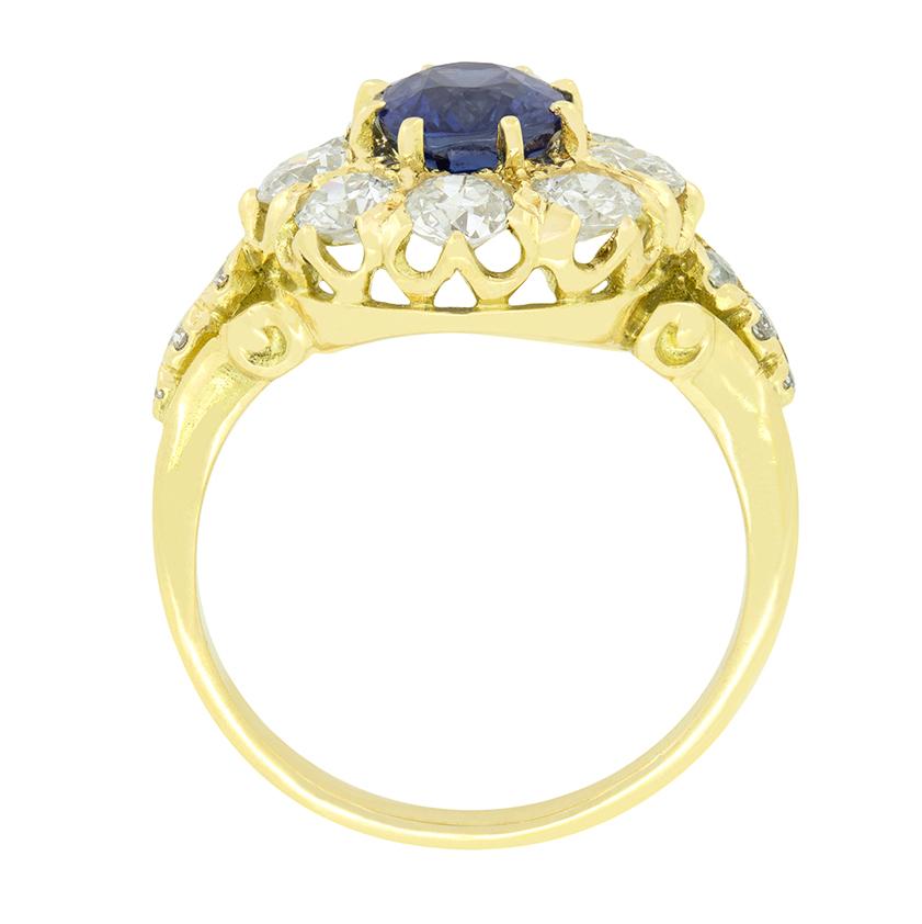 In der Mitte dieses wunderschönen Clusterrings befindet sich ein lebhaft blauer, erhitzter Saphir mit einem Gewicht von 1,20 Karat. Der Stein ist in 18 Karat Gelbgold gefasst und von einem Heiligenschein aus funkelnden Diamanten im Altschliff