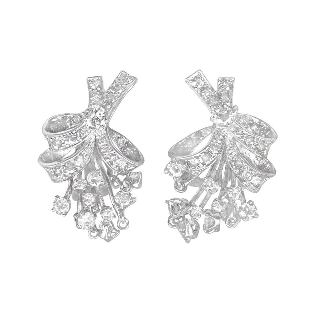 Capture the essence of mid-century charm with these delightful diamond spray earrings. A graceful fusion of floral and bow motifs, they feature prong-set transitional cut diamonds suspended on wires beneath a diamond-studded ribbon, evoking the