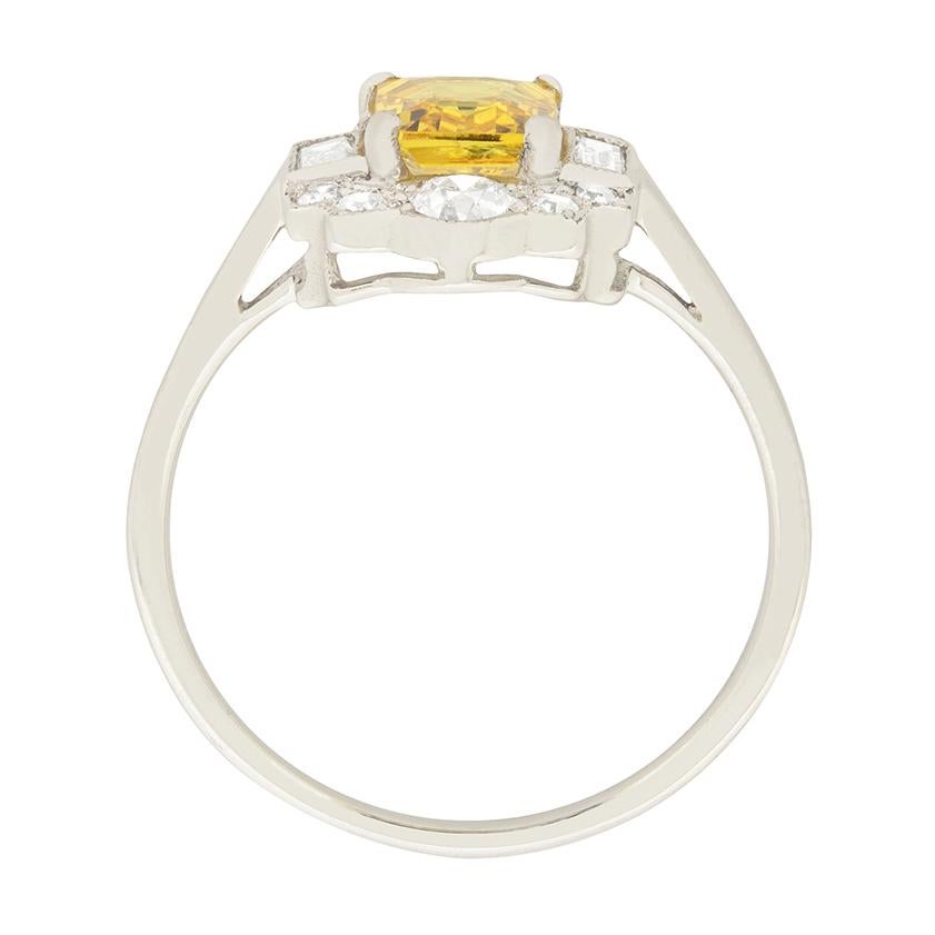 A lovely yellow sapphire shines at the centre of this vintage ring. The 1.20 carat sapphire is emerald-cut. Surrounding the sapphire is 0.46 carat of round brilliant diamonds and 0.20 carat of baguette cut diamonds, placed in a beautiful pattern.