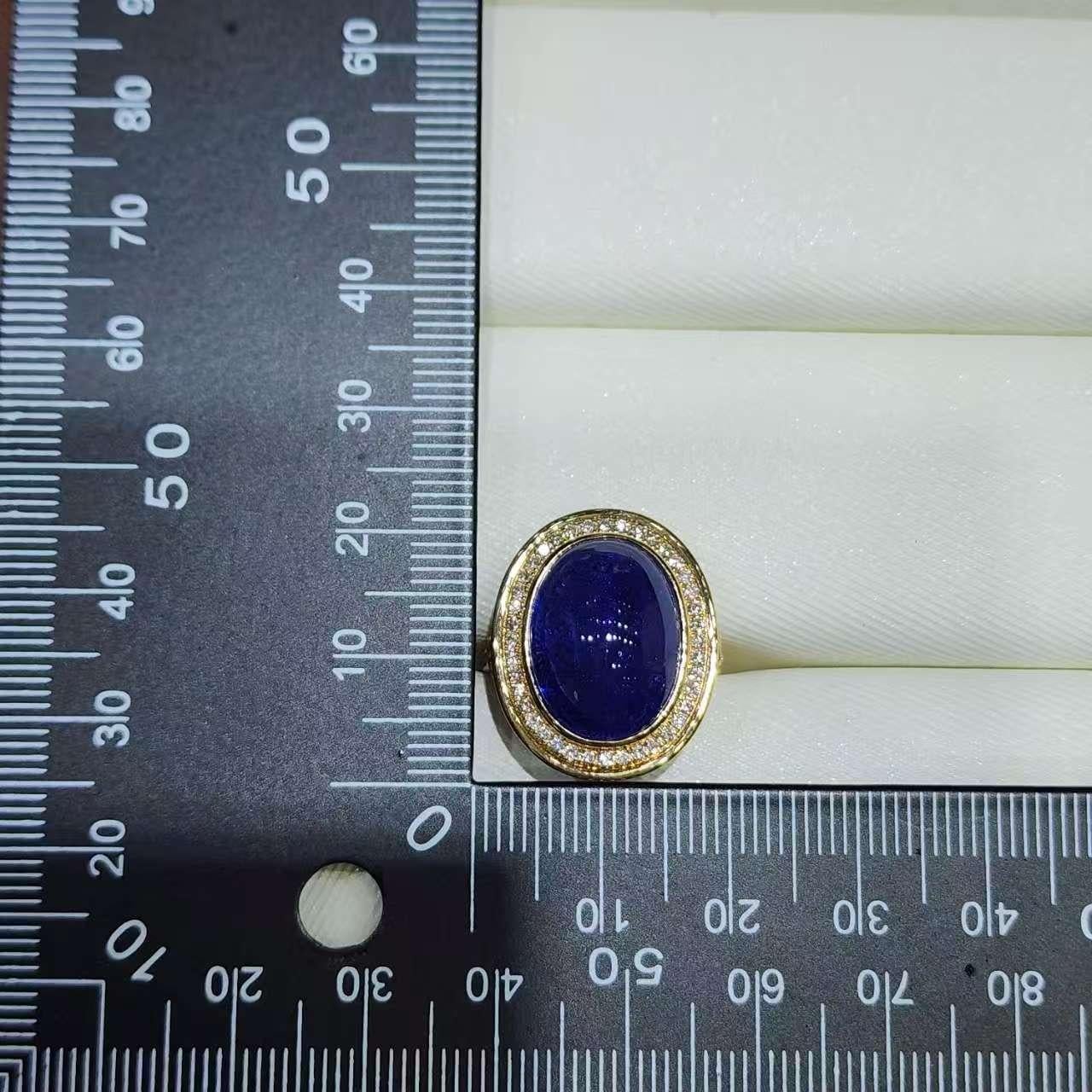 Dieser auffällige Cocktailring ist mit einem ovalen 12,47-karätigen Tansanit-Cabochon in 18-karätigem Gelbgold gefasst. Der satte violettblaue Stein leuchtet mit natürlicher Tiefe und innerer Brillanz, akzentuiert durch einen funkelnden Halo aus