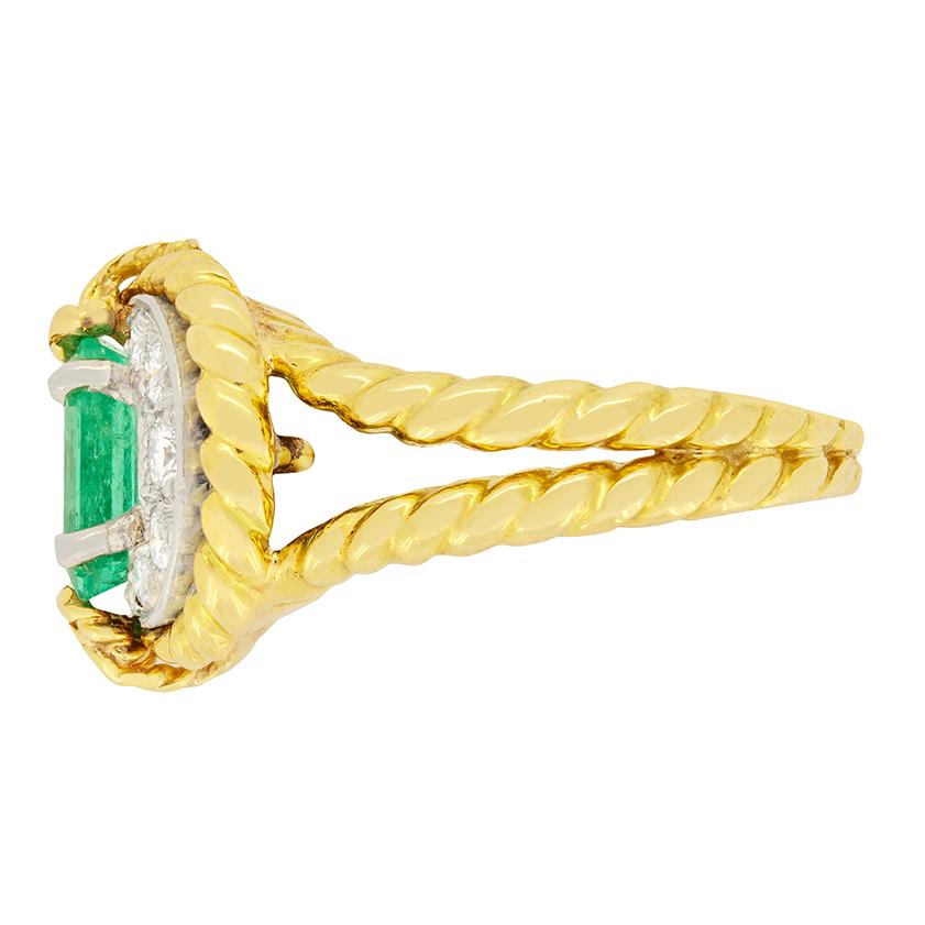 This show stopping cocktail ring was crafted in the 1950s. The 1.25 carat emerald cut emerald is fully natural with no signs of treatment. The gem stone is claw set into platinum and surrounded by ten round brilliant diamonds totalling 1.00 carat.