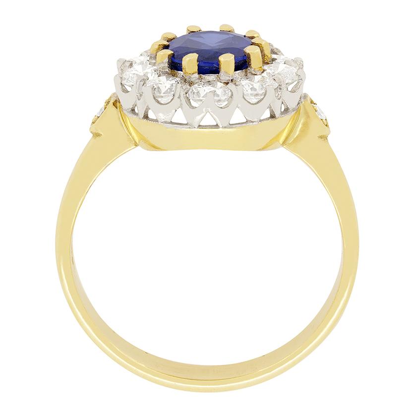 A lively oval cut sapphire, weighing 1.25 carat, sits proudly in this vintage cluster ring. Surrounding the sapphire is a bright halo of ten round brilliant cut diamonds. These diamonds total to 1.00 carat and have been estimated as I in colour and