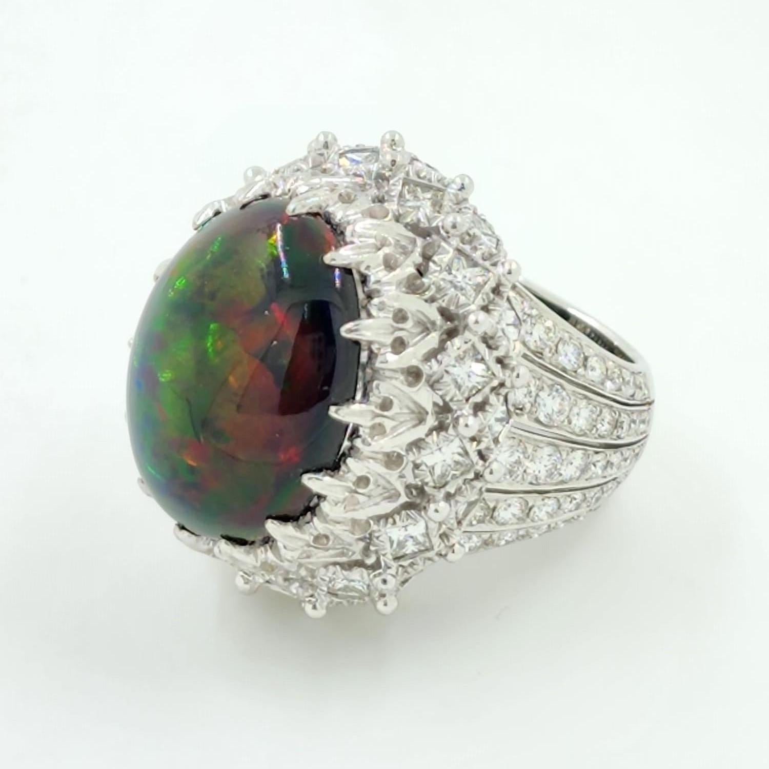 Introducing our stunning black opal ring, a true work of art that combines exquisite design with the natural beauty of a 12.93 carat black opal. The opal exhibits a captivating multi-color pattern that ranges from pigeon blood red to green and