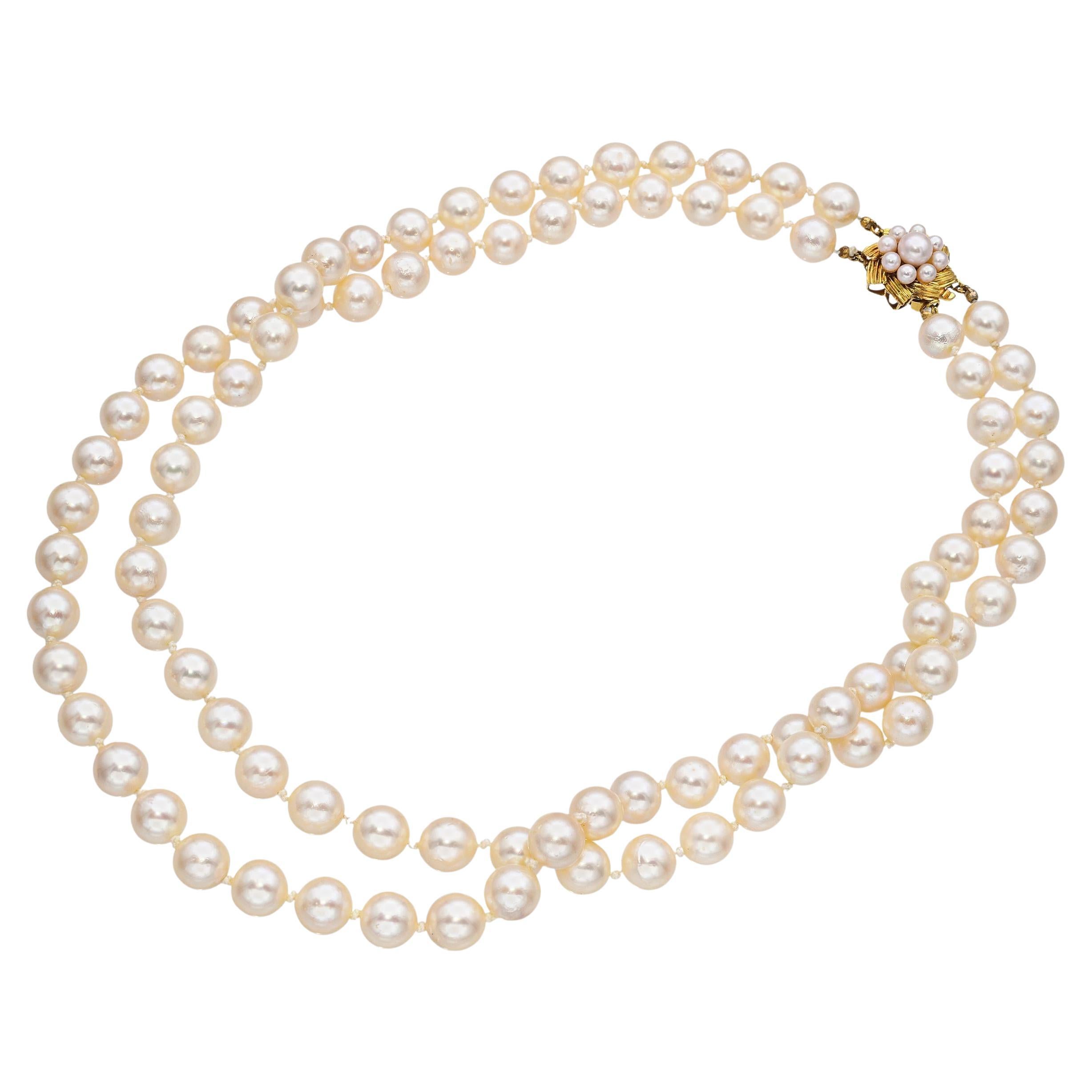This vintage double strand necklace showcases luminous cultured pearls strung in elegant symmetry, secured by a 12k yellow gold clasp. The pearls display a soft creamy luster with slight natural variation, adding depth and character to the piece.