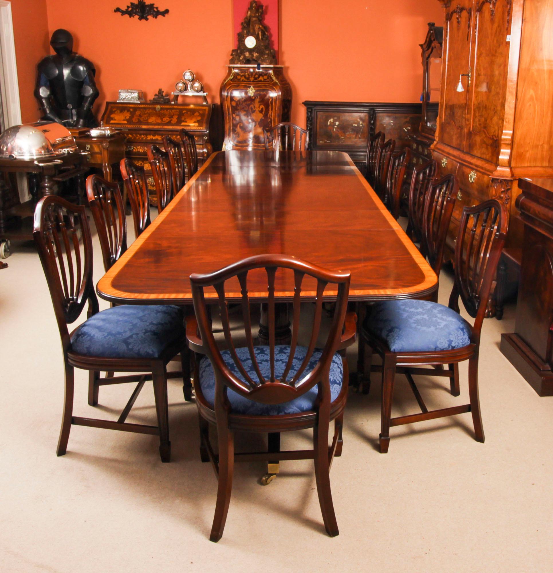This is a superb dining set comprising a 13ft Vintage Regency Revival dining table  with fourteen Hepplewhite revival dining chairs., dating from the second half of the 20th Century.

The tabletop was crafted in flame mahogany and features superb