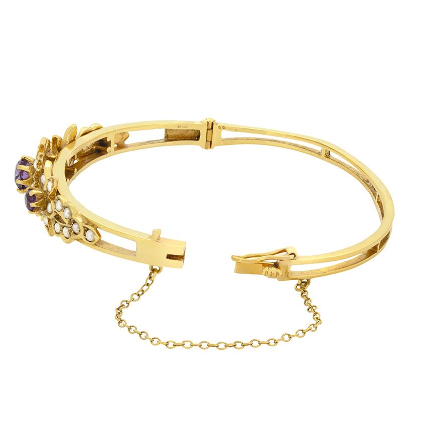A floral design adorned with amethyst and pearls form the central display in this charming vintage bangle. The largest amethyst sits central, weighing 0.80 carat with an additional two 0.25 carat amethyst flanking. Forming the petals around each
