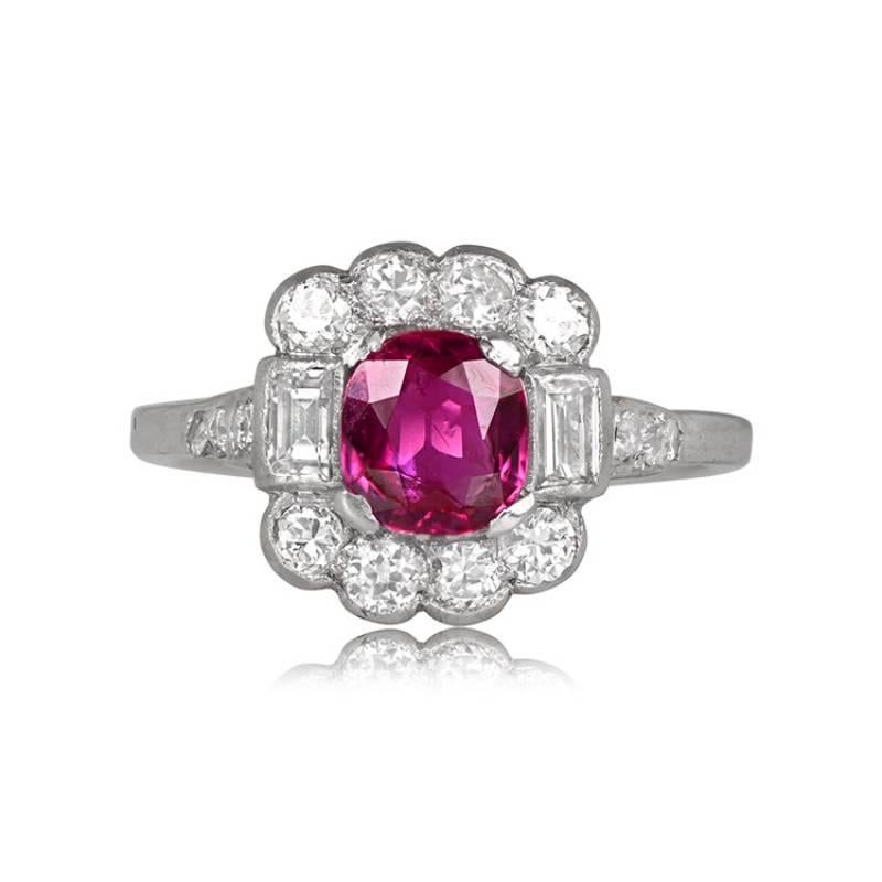 A vintage platinum ring features a 1.30-carat cushion-cut ruby, accented by baguette-cut diamonds on either side. The ring exhibits an Edwardian-era floral design with round brilliant-cut diamonds surrounding the center stone, while smaller round