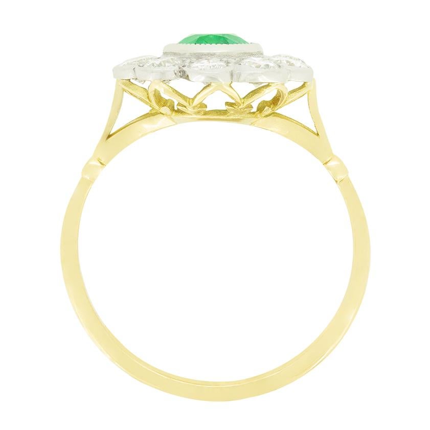 Une magnifique émeraude verte occupe le devant de la sc�ène dans cette bague à grappes vintage. L'émeraude de taille ovale pèse 1,30 carat et est sertie en platine. Autour de la pierre centrale, un total de 1.50 carat de diamants ronds de taille