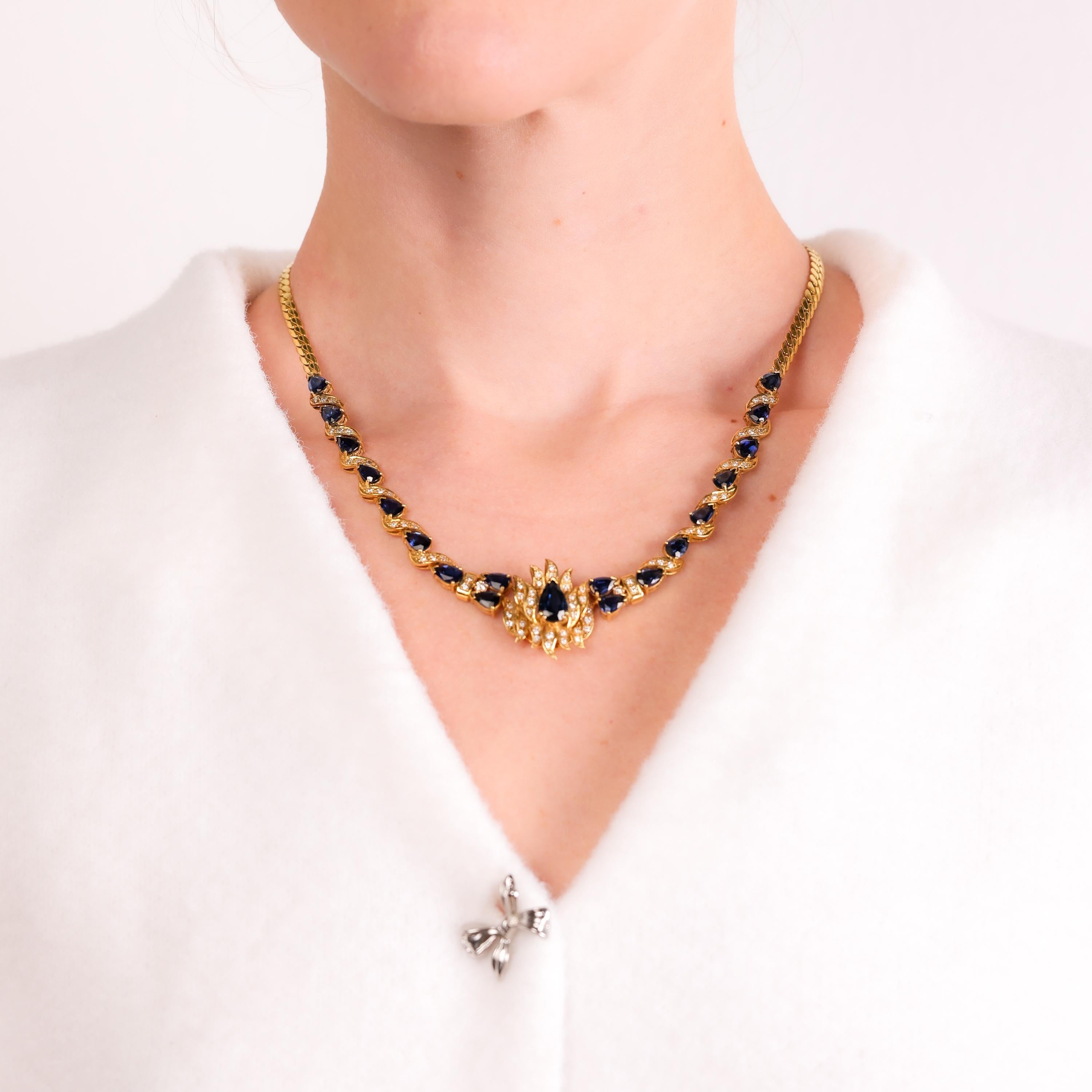 This stunning vintage cocktail necklace showcases rich blue sapphires and radiant diamonds in a timeless 14k yellow gold design, exuding elegance and sophistication.

Total sapphire weight: Approximately 13.30 carats
Center stone: Pear cut deep blue
