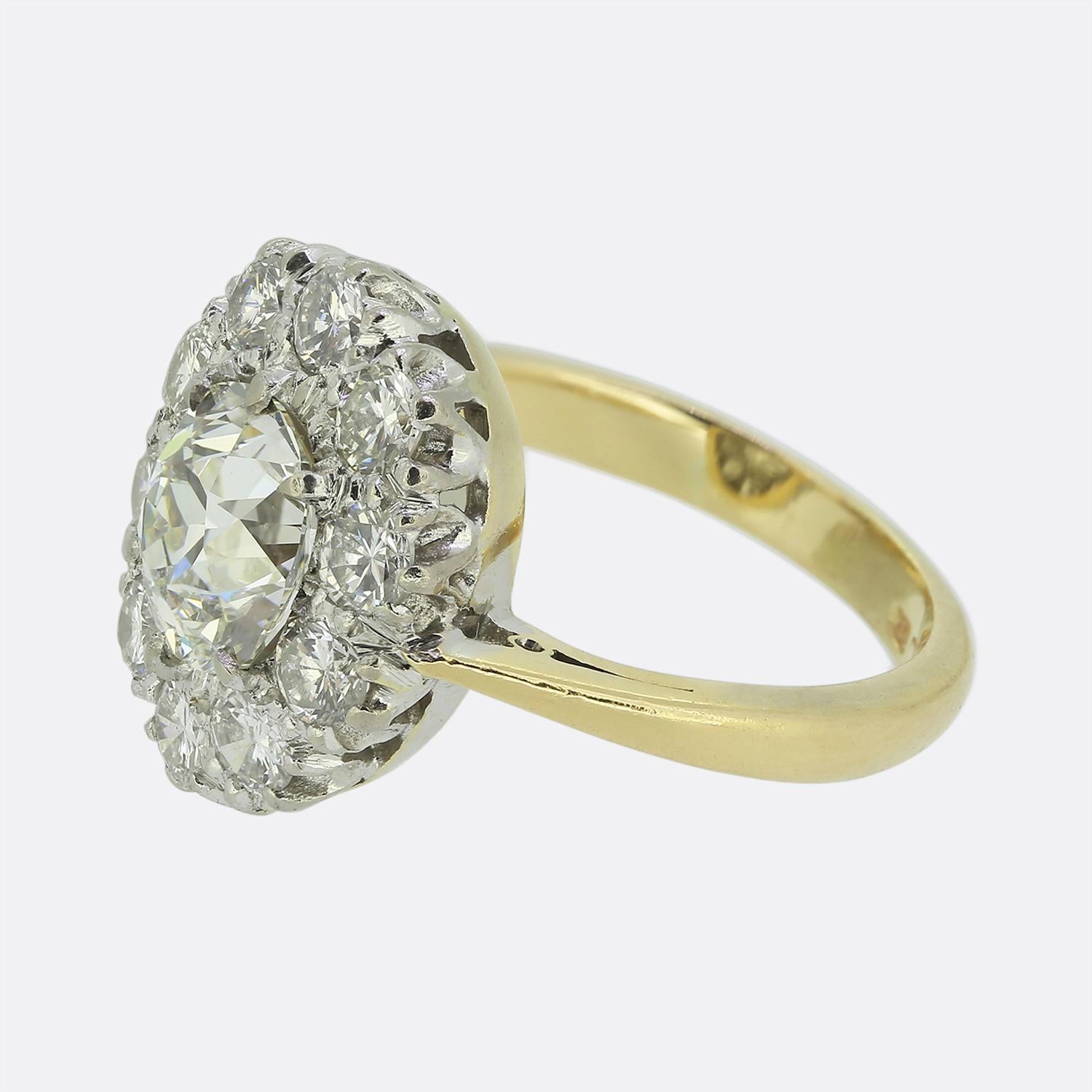 Hier haben wir einen exquisiten Clusterring, in dessen Zentrum ein atemberaubender Diamant im Altminenschliff steht, der einen fesselnden weißen Glanz ausstrahlt. Der Mittelstein ist von einer einzigen Reihe runder Diamanten umgeben, von denen jeder