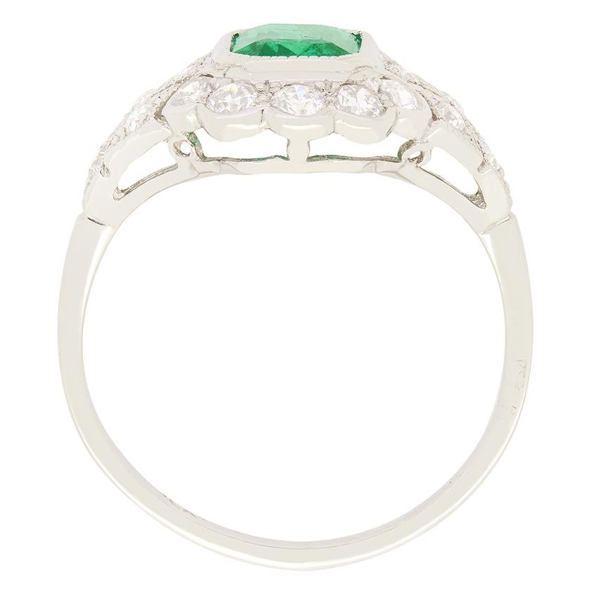 Dieser bezaubernde Cluster-Ring im Vintage-Stil der 1970er-Jahre zeigt in seiner Mitte einen leuchtenden Smaragd von 1,35 Karat im Smaragdschliff. Den Smaragd umgibt ein schimmernder Kranz von Diamanten im Altschliff mit einem Gesamtgewicht von 0,70