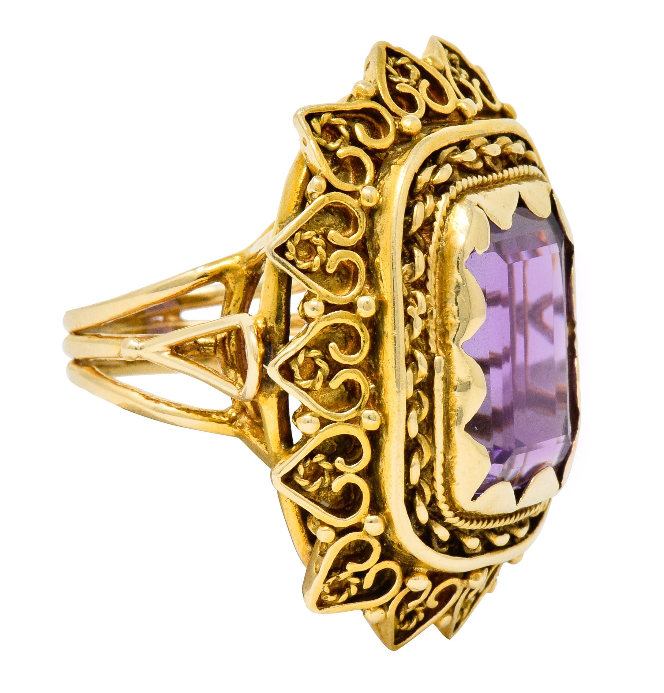 Centering an emerald cut amethyst weighing approximately 13.64 carats, transparent and a medium-light purple color

Set in place by scalloped polished gold and surrounded by twisted rope and chain link motifs

With radiating petal-like surround