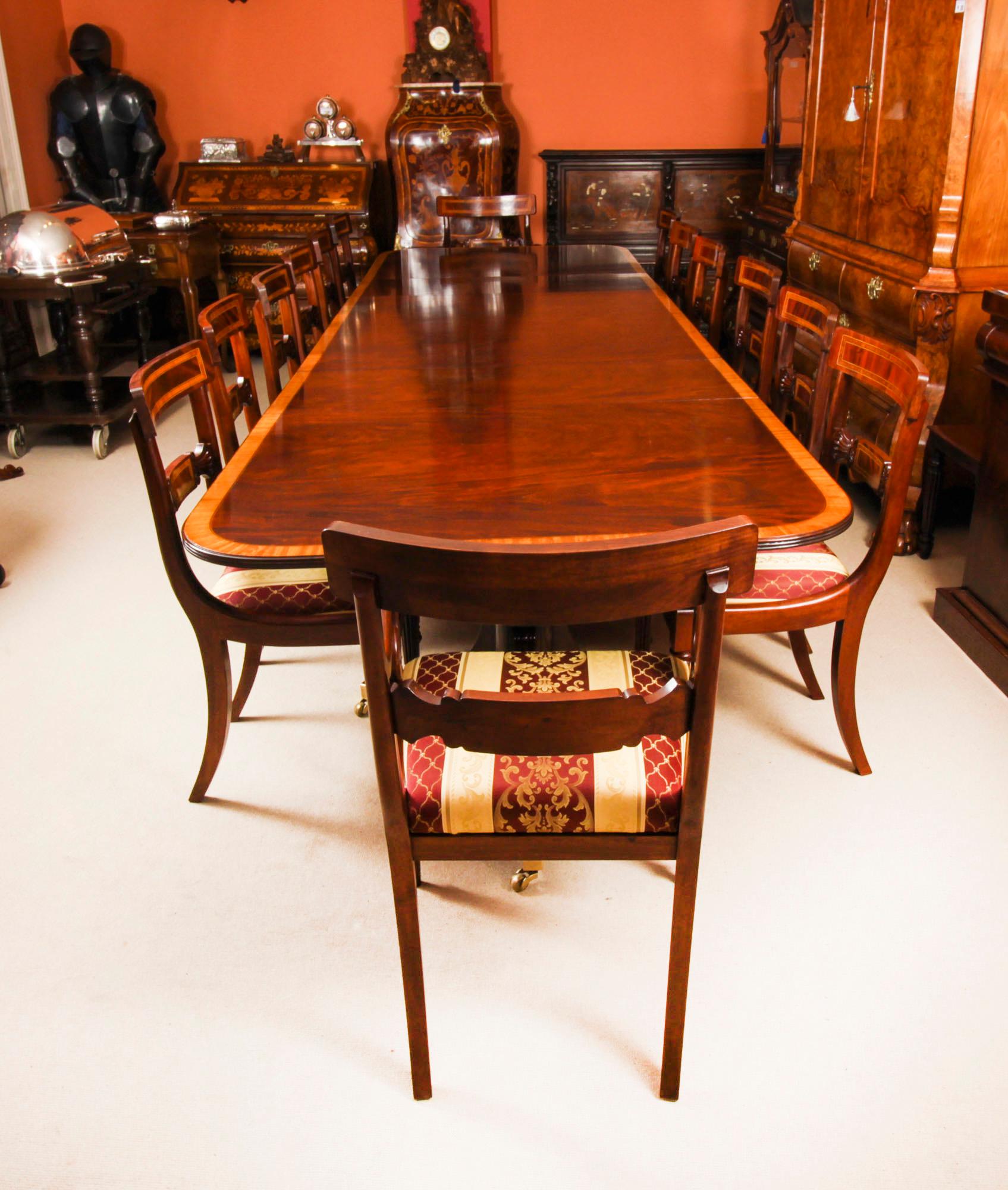 This is a superb dining set comprising a 13ft Vintage Regency Revival dining table  with fourteen Hepplewhite revival dining chairs., dating from the second half of the 20th Century.

The tabletop was crafted in flame mahogany and features superb