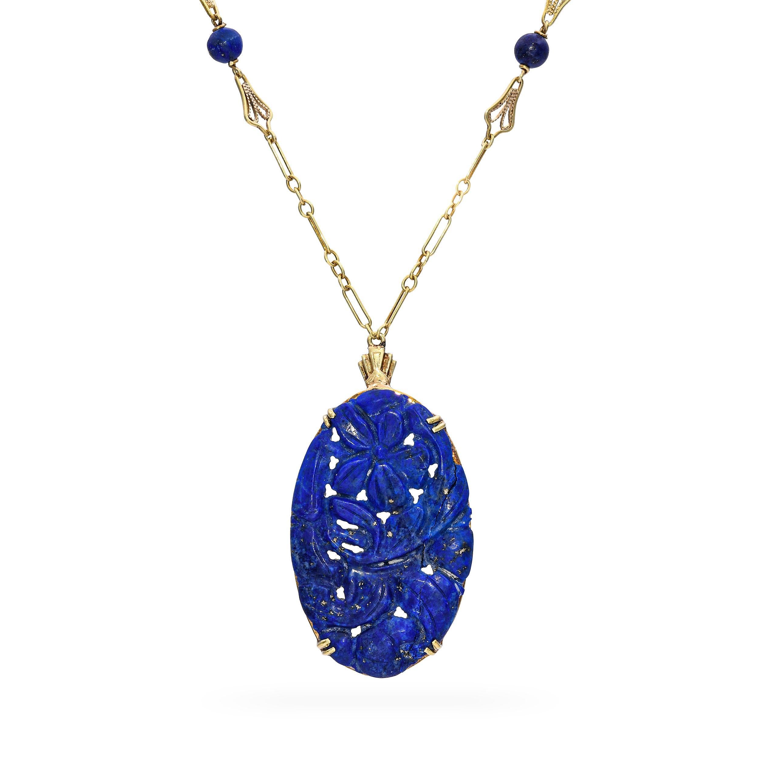 Questa collana vintage in oro giallo 13k con ciondolo in lapislazzuli intagliato presenta una splendida pietra di lapis blu intenso con macchie di pirite dorata naturale, sapientemente intagliata in un design ornato. Il ciondolo è incorniciato in