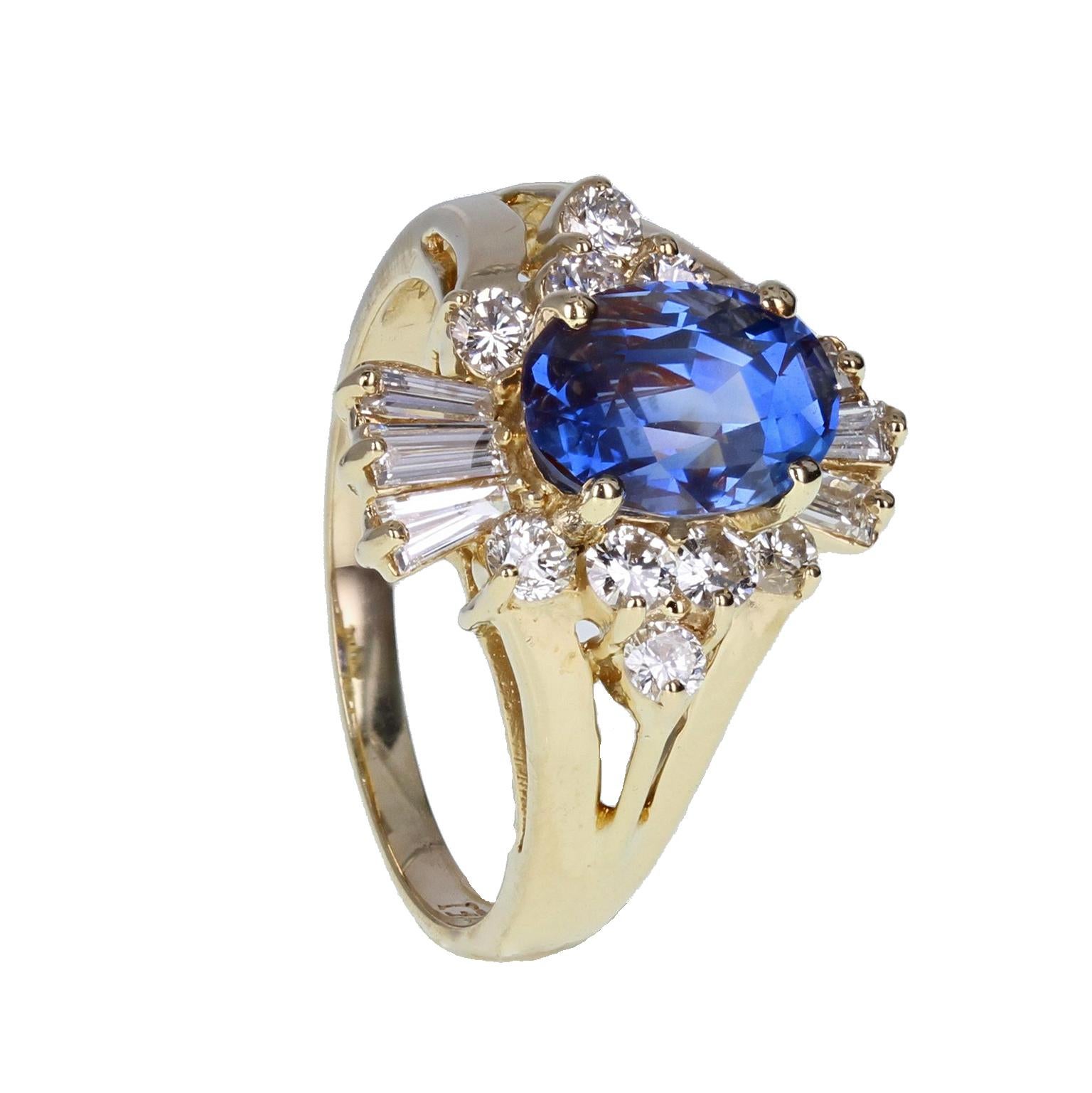 A beautifully crafted sapphire and diamond cluster ring. The central oval-cut blue sapphire of approximately 2.30 carats mounted in four 14-carat gold claws. Surrounded by a cluster of brilliant-cut diamonds and two fan motifs of tapered