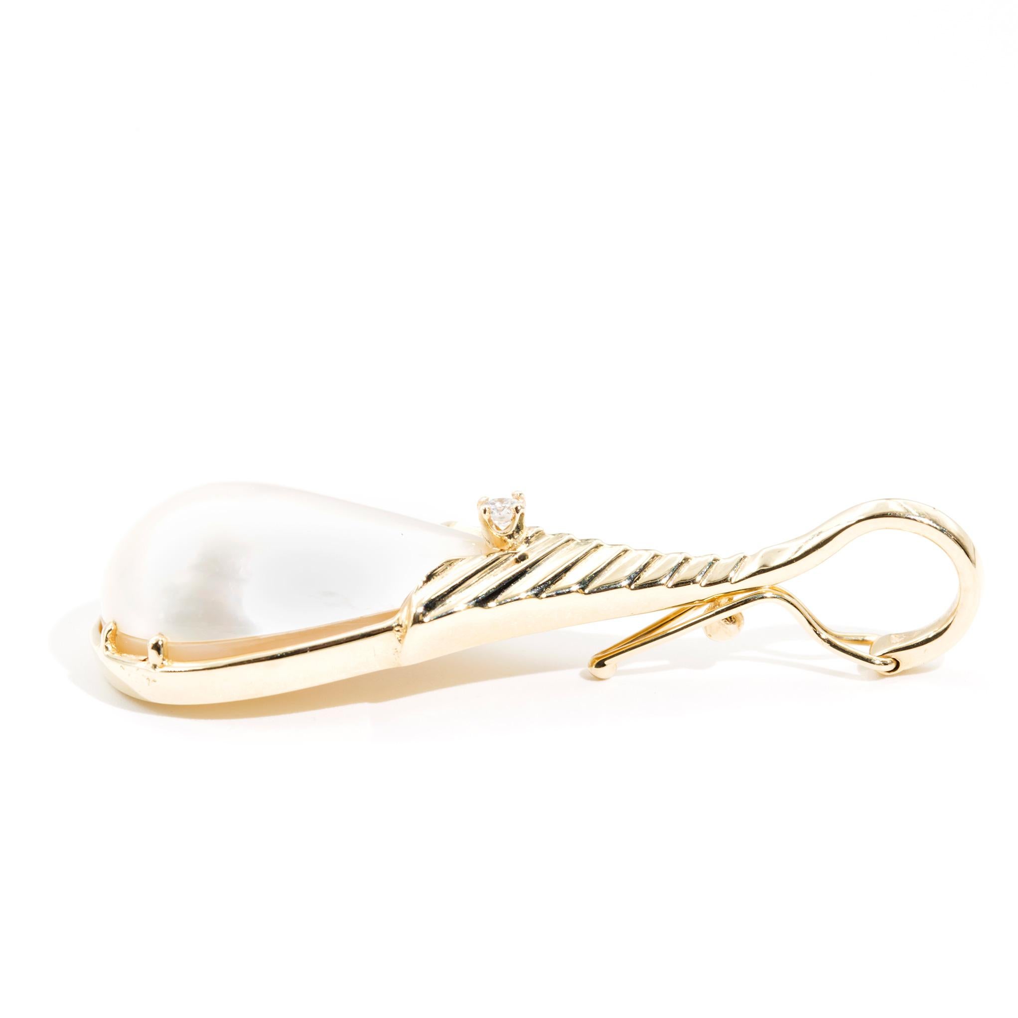 Carefully crafted in 14 carat yellow gold, this charming vintage pendant features a lovely pear shape lustrous mabe pearl nestled in a wheat pattern bezel setting finished with a single round brilliant cut diamond. This gorgeous pendant is fitted