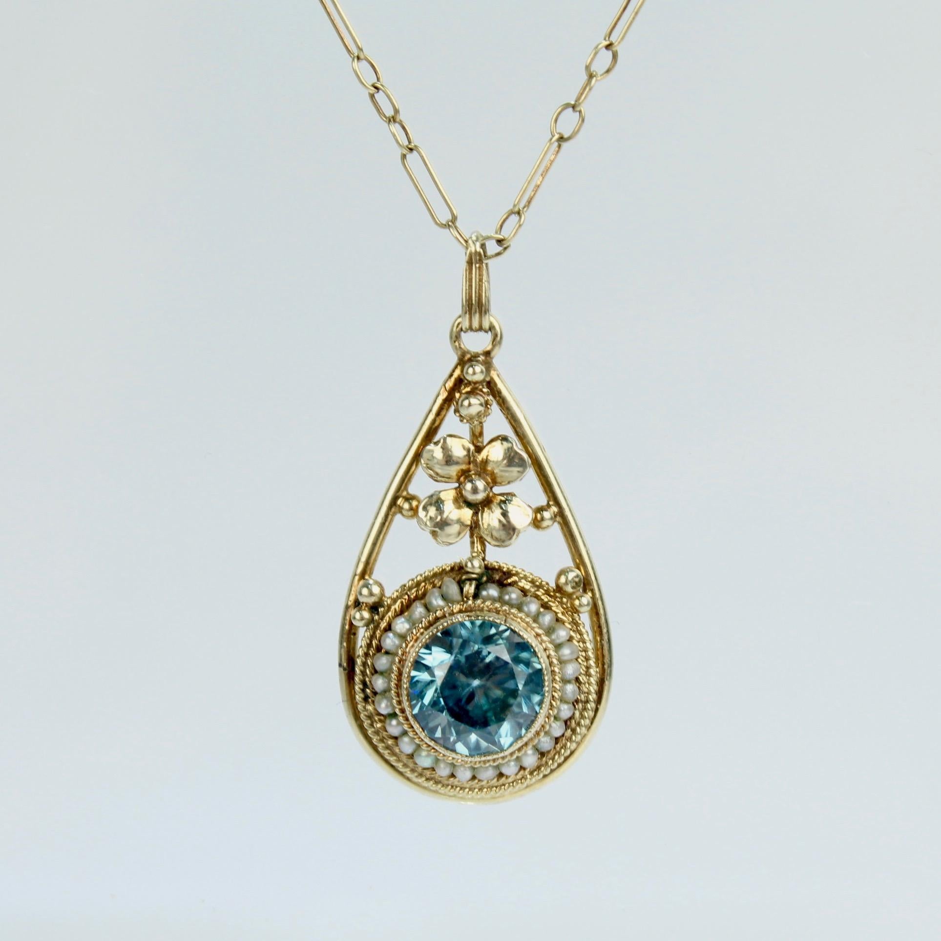 A fine gold, blue topaz & pearl teardrop necklace.

In 14k yellow gold with a 3 tiers of gold coils and seed pearls surrounding a bezel set blue topaz below a gold flower. 

Simply a wonderful necklace!

Date:
20th Century

Overall Condition:
It is