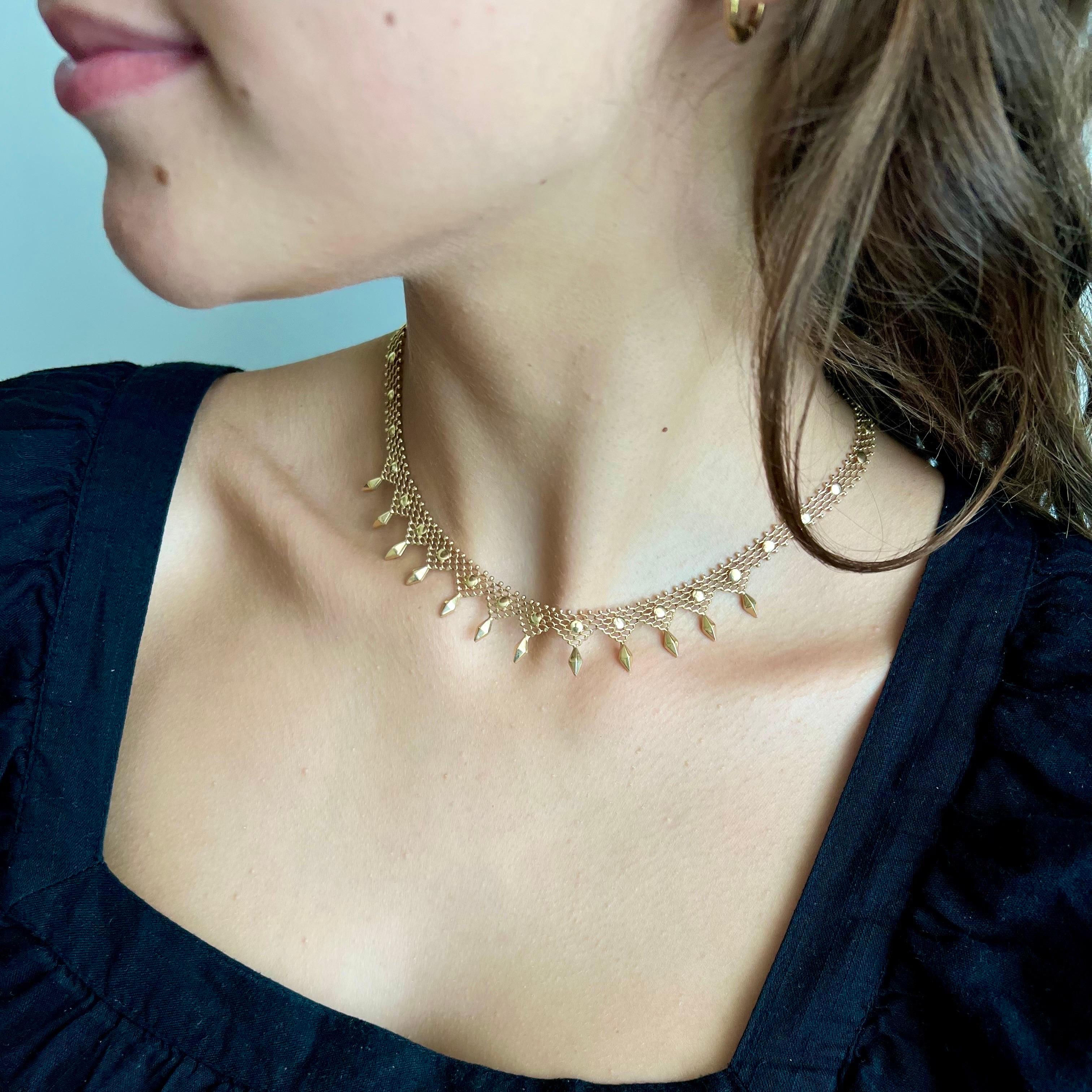 A timeless vintage woven choker chain necklace created in 14 karat gold. The chain of the necklace is beautifully made and represents twelve diamond-shaped figures and small balls on the side of the chain. The links are all nicely put together,