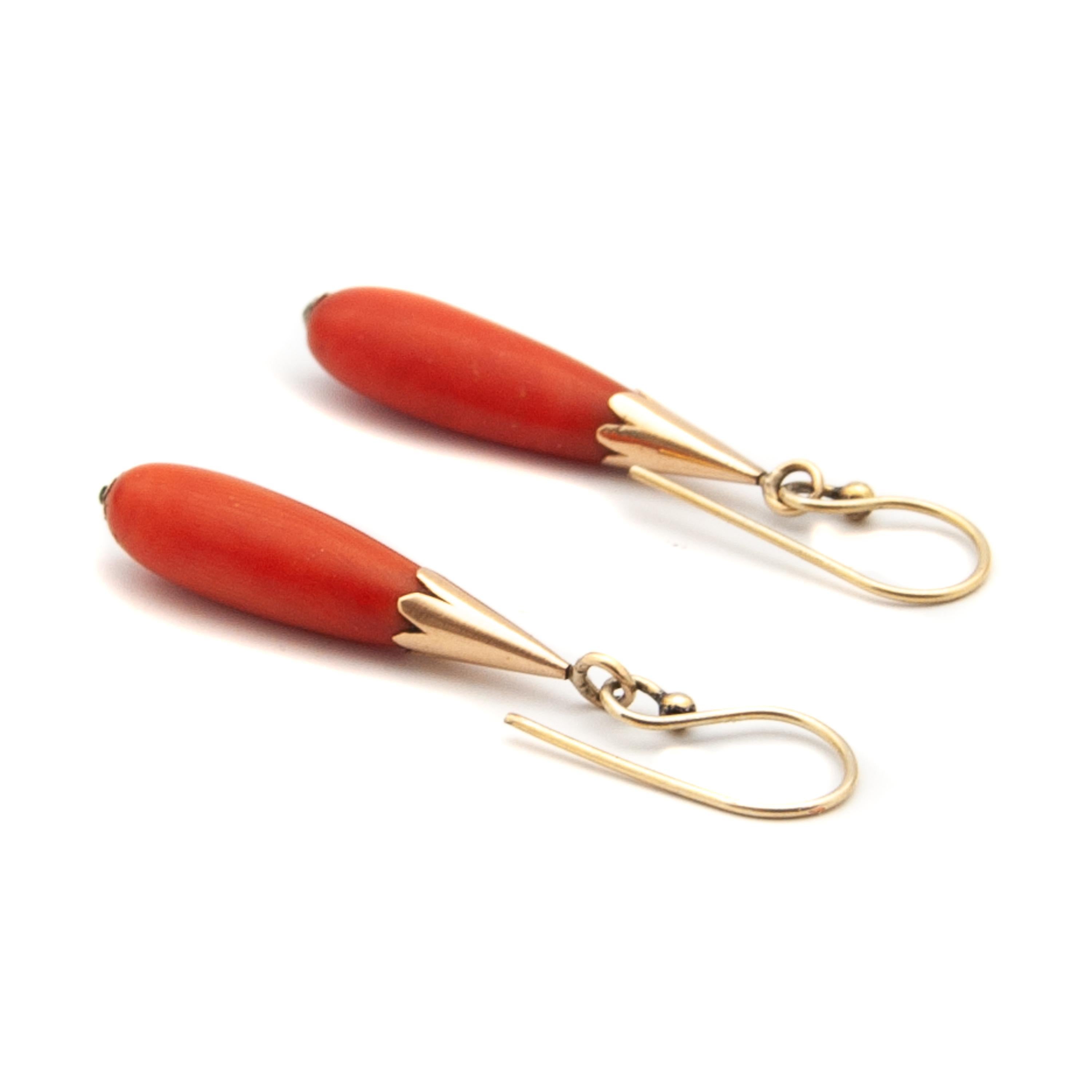 Pair of coral dangle earrings made of 14 karat yellow gold. The earrings have beautifully coral drop-shaped pendants, set in gold jagged caps. The gold caps have fringed edges. 

The *coral earrings are in good condition. The coral differ slightly